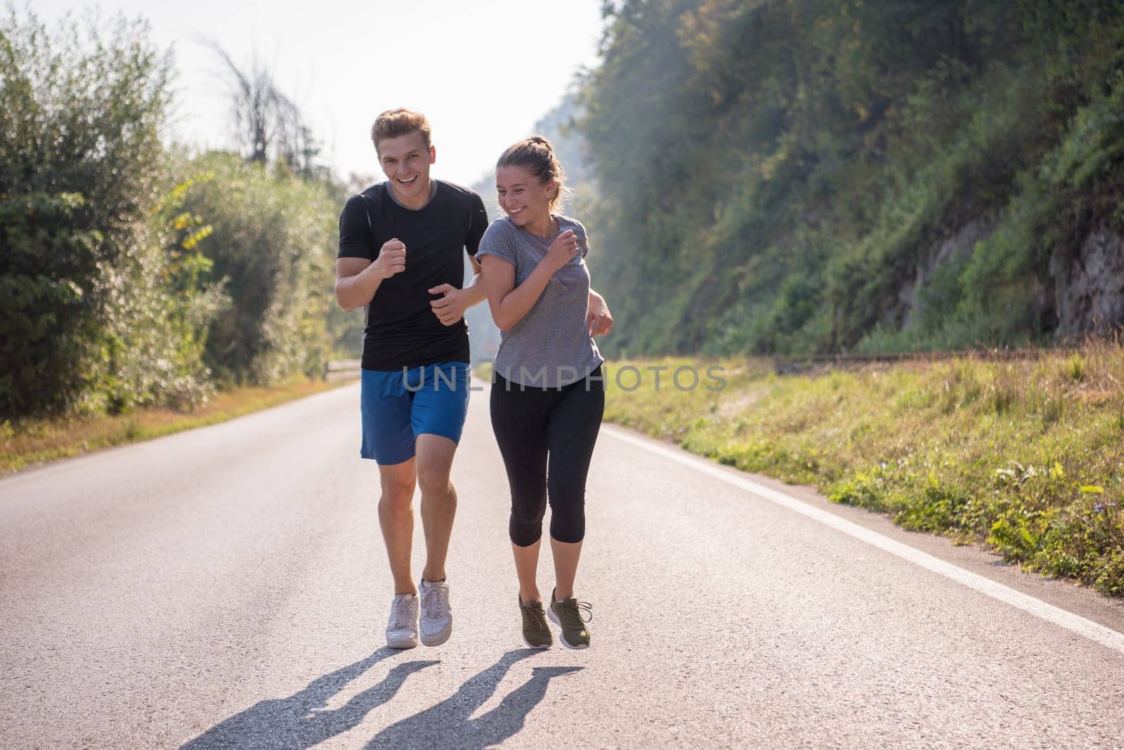 young couple enjoying in a healthy lifestyle while jogging along a country road, exercise and fitness concept