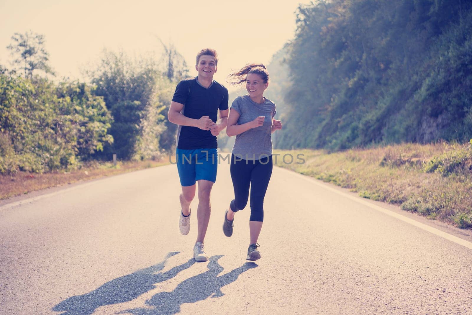 young couple enjoying in a healthy lifestyle while jogging along a country road, exercise and fitness concept