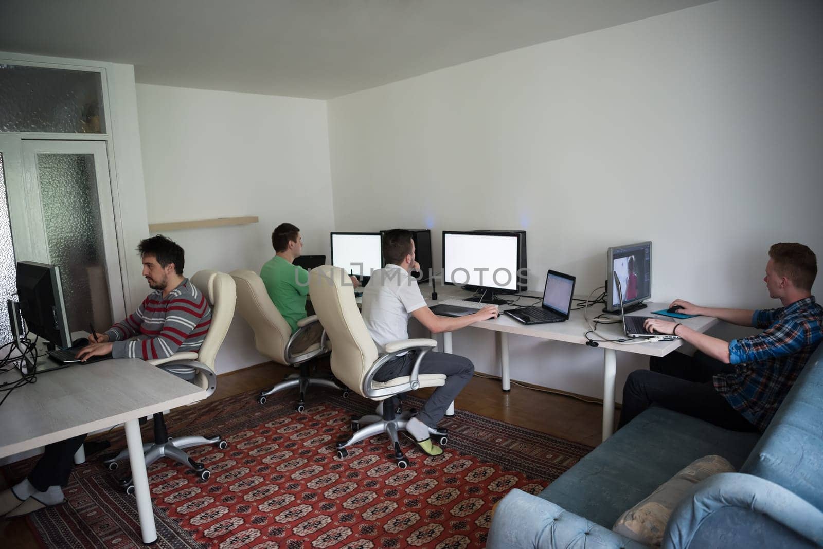a group of young graphic designers working on a digital tablet and a computer