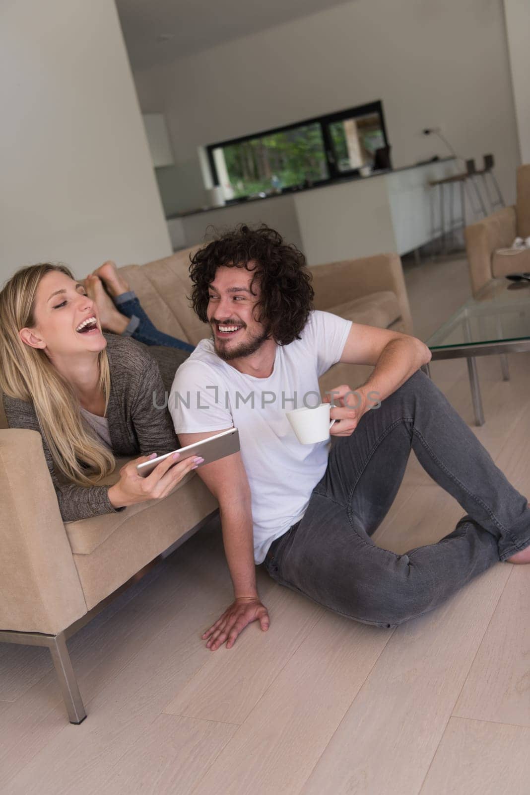 Young couple relaxing at luxurious home with tablet computers reading in the living room on the sofa couch.