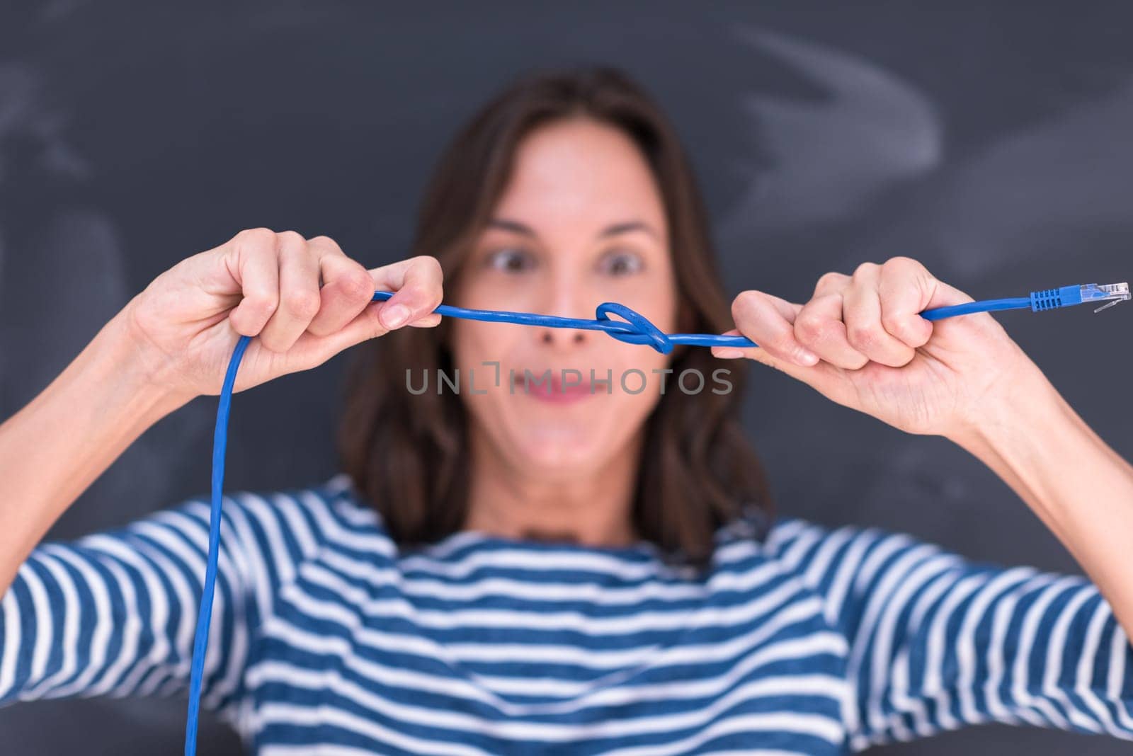 portrait of a young woman holding a internet cable in front of chalk drawing board
