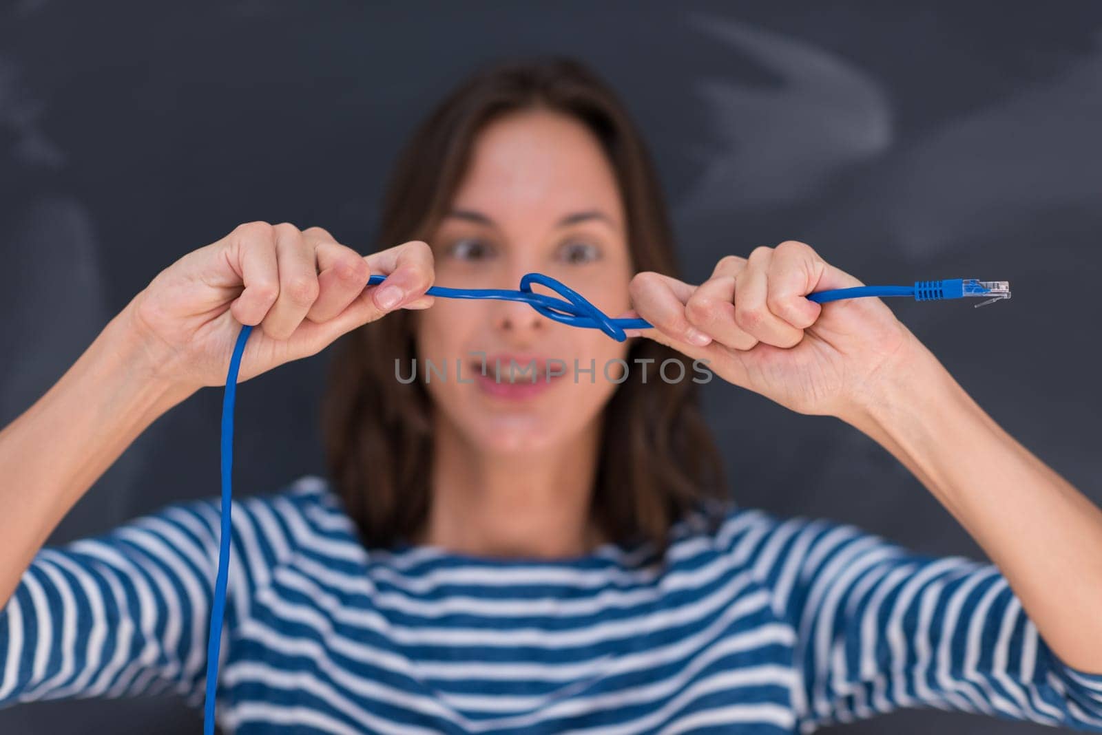 portrait of a young woman holding a internet cable in front of chalk drawing board
