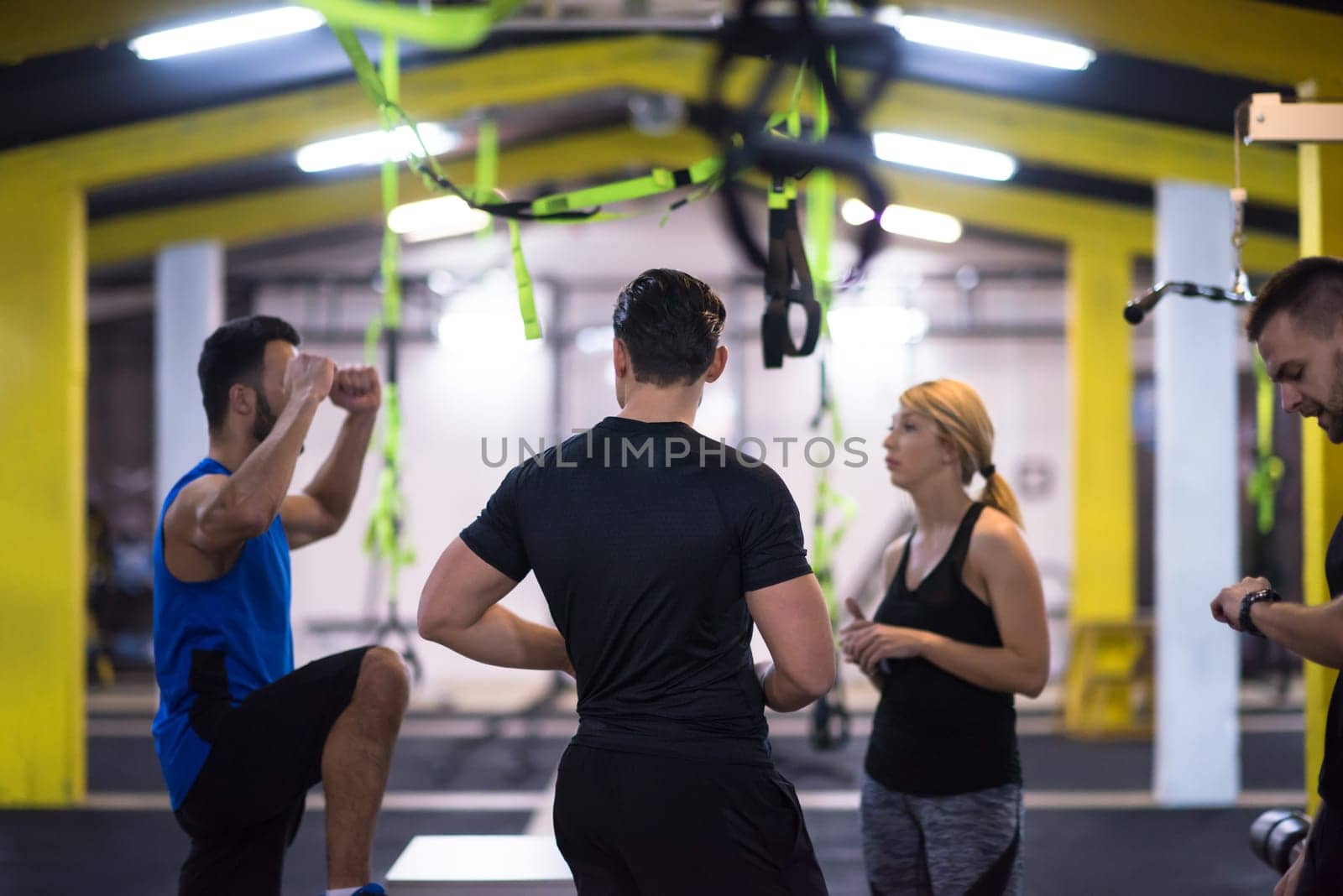 group of young healthy athletic people training jumping on fit box at cross fitness gym