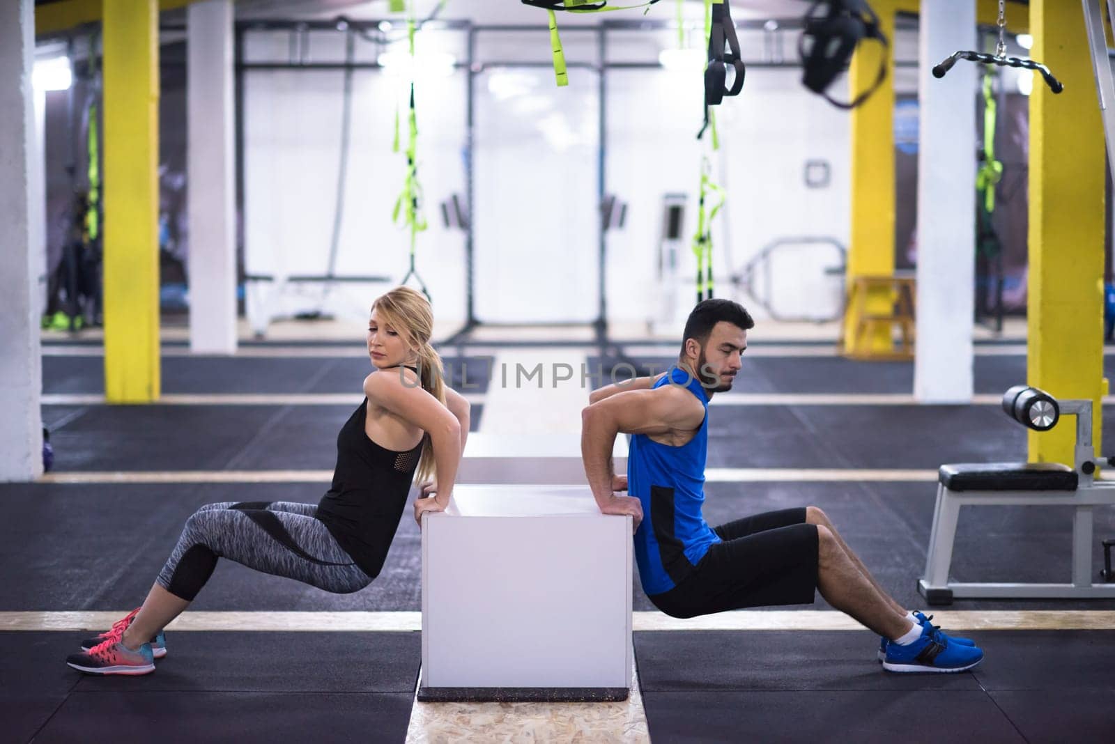 young couple athletes working out their arms using boxes at cross fitness gym
