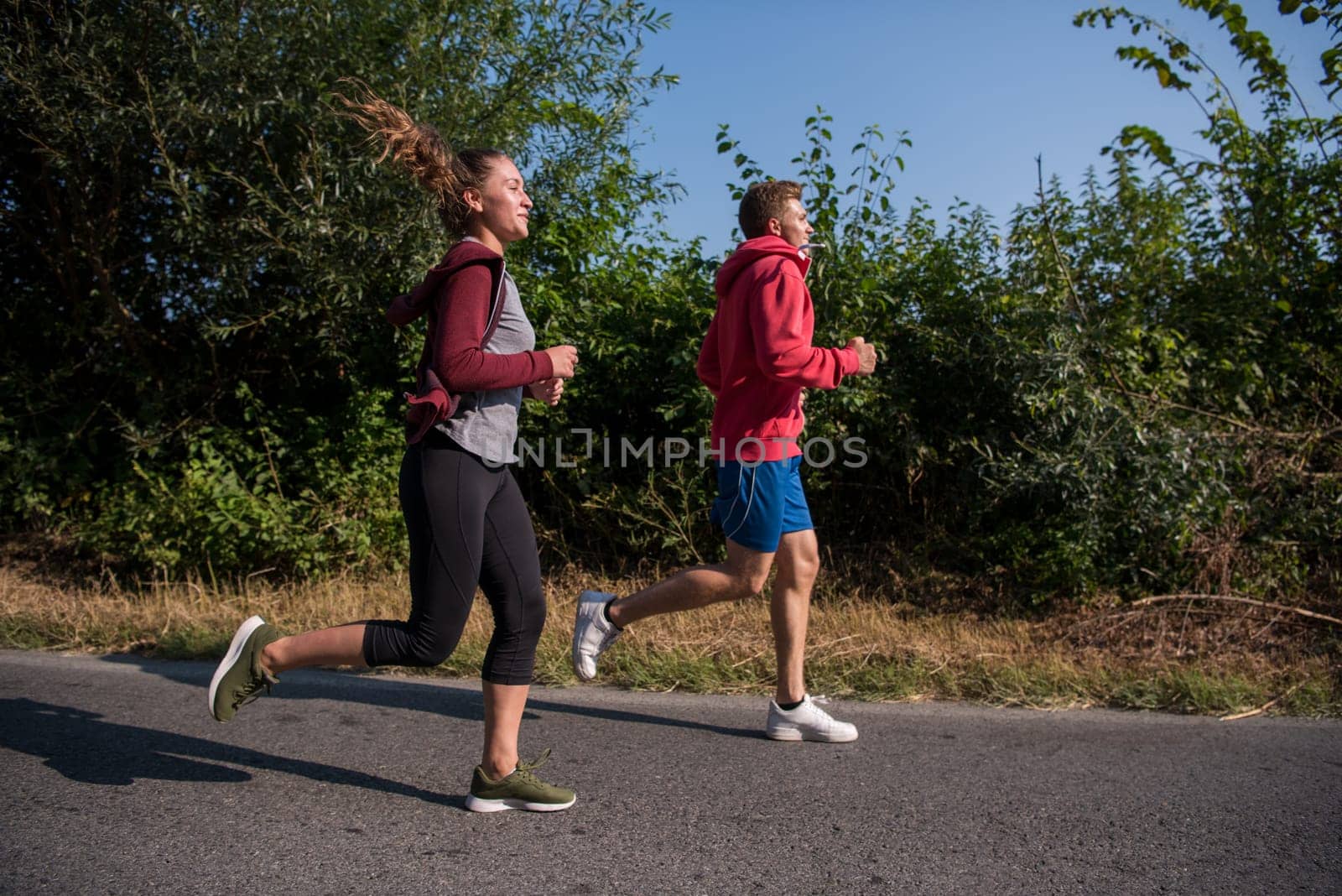 young couple enjoying in a healthy lifestyle while jogging along a country road, exercise and fitness concept