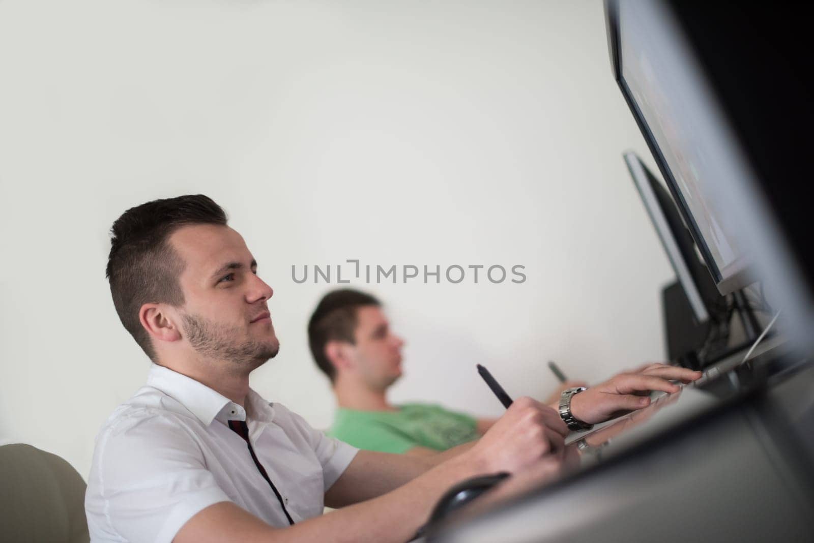 a group of young graphic designers working on a digital tablet and a computer