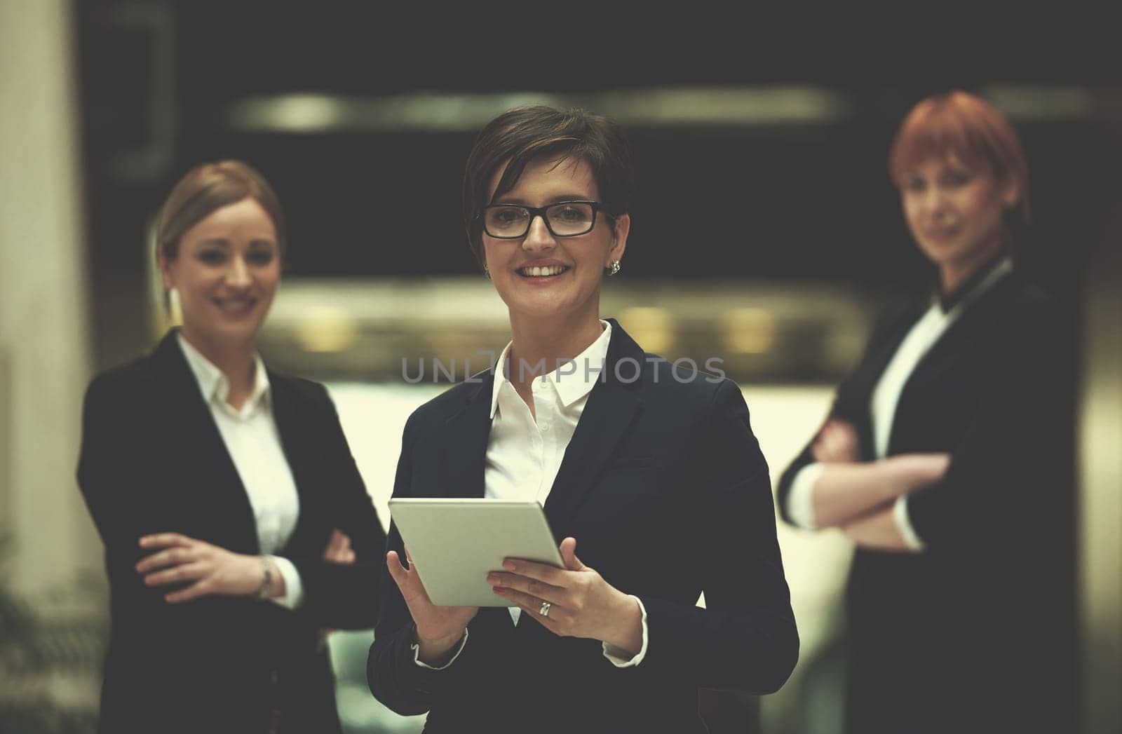 young business woman group,  team standing in modern bright office and working on tablet computer