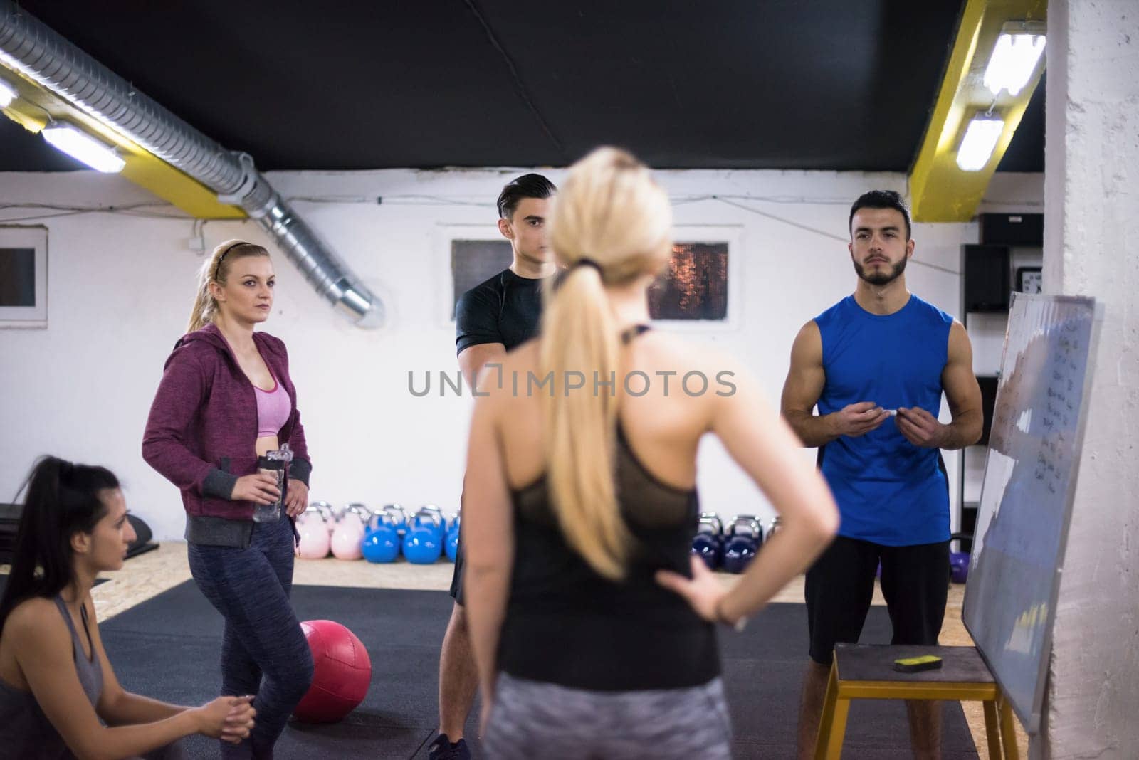 Training course.group of young athletes getting instructions from trainer before exercise at cross fitness gym