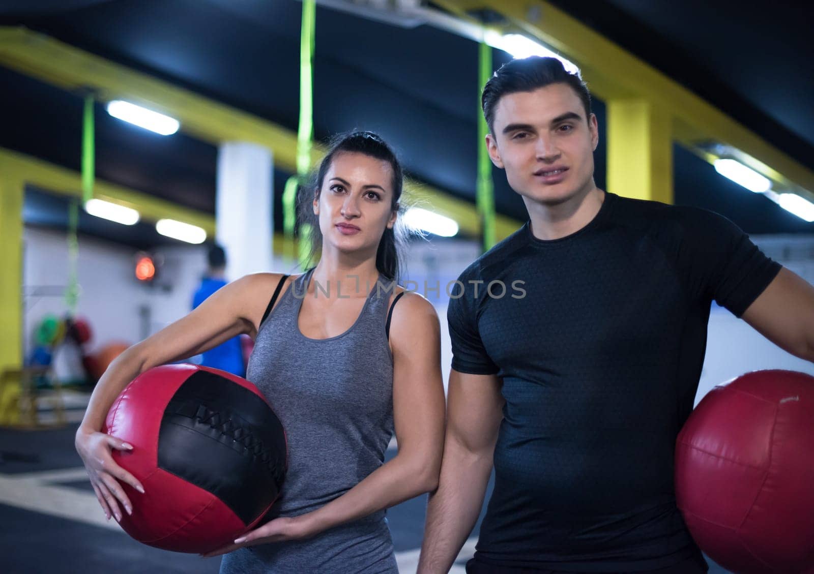 young athletes couple working out with medical ball at cross fitness gym