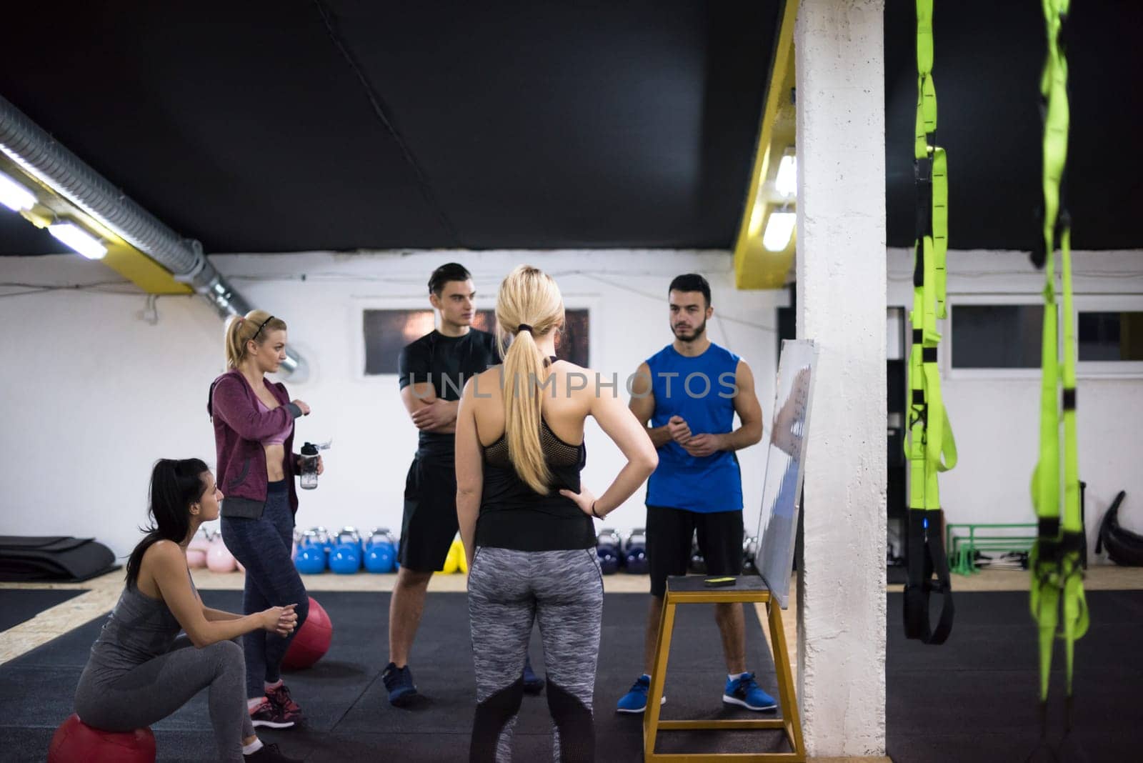 Training course.group of young athletes getting instructions from trainer before exercise at cross fitness gym