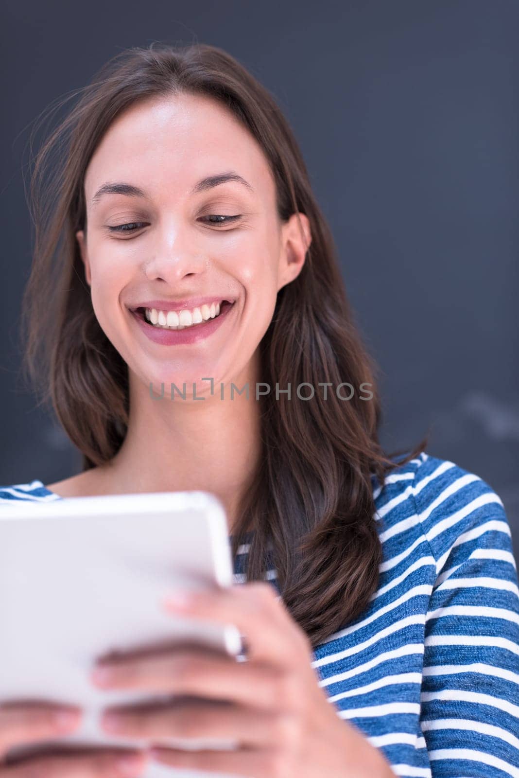 Happy young woman using tablet computer in front of chalk drawing board