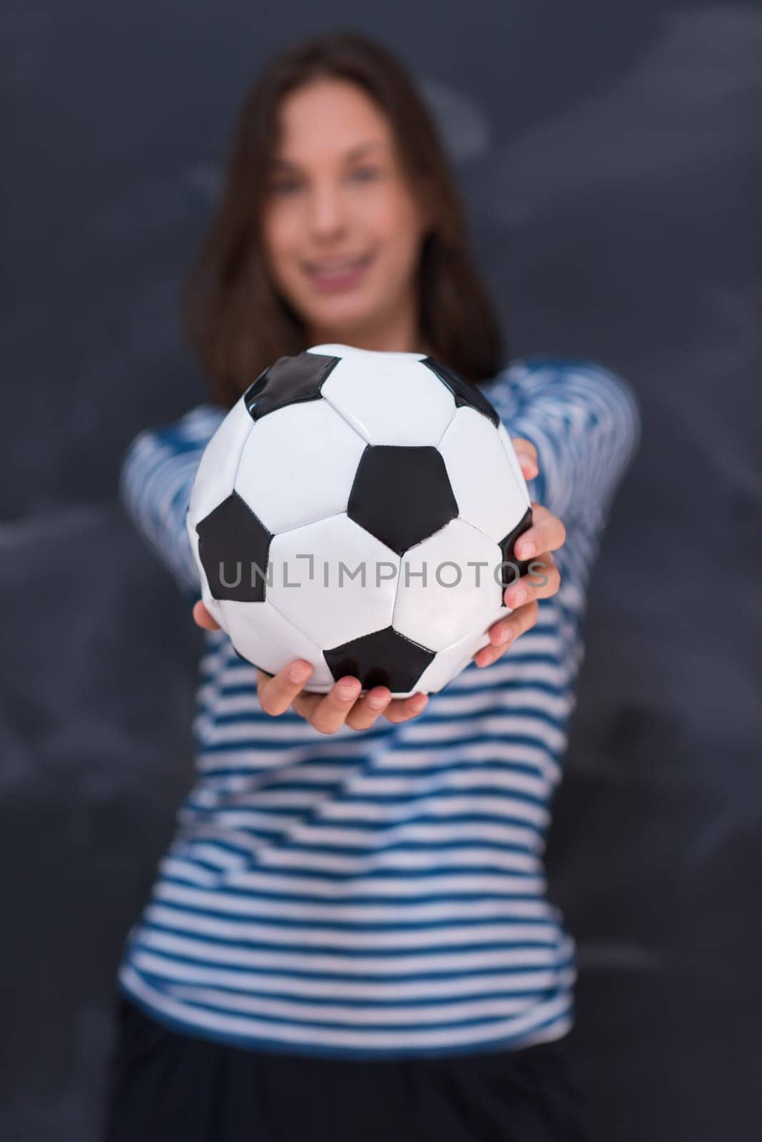 portrait of a young woman holding a soccer ball in front of chalk drawing board