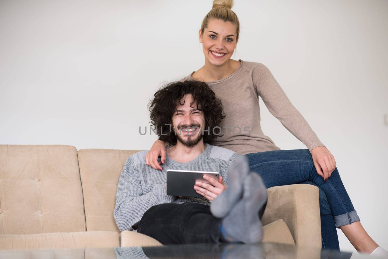 Young couple relaxing at luxurious home with tablet computers reading in the living room on the sofa couch.