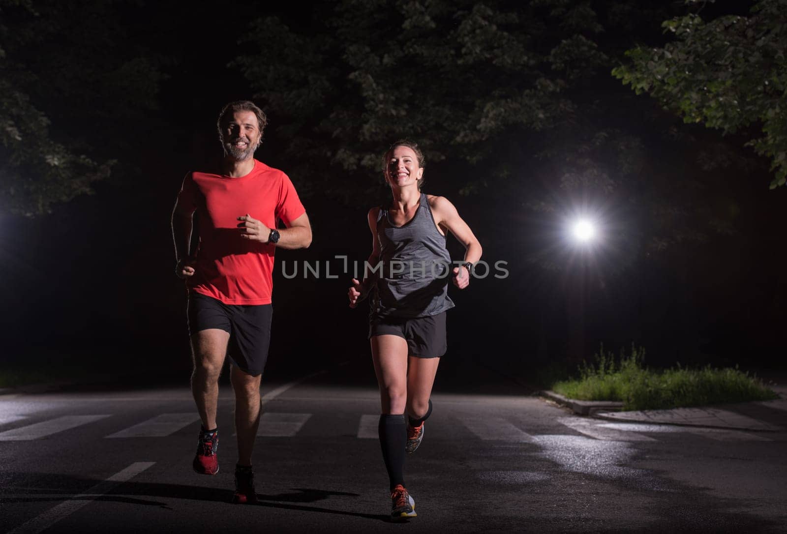 group of healthy people jogging in city park, runners team at night training