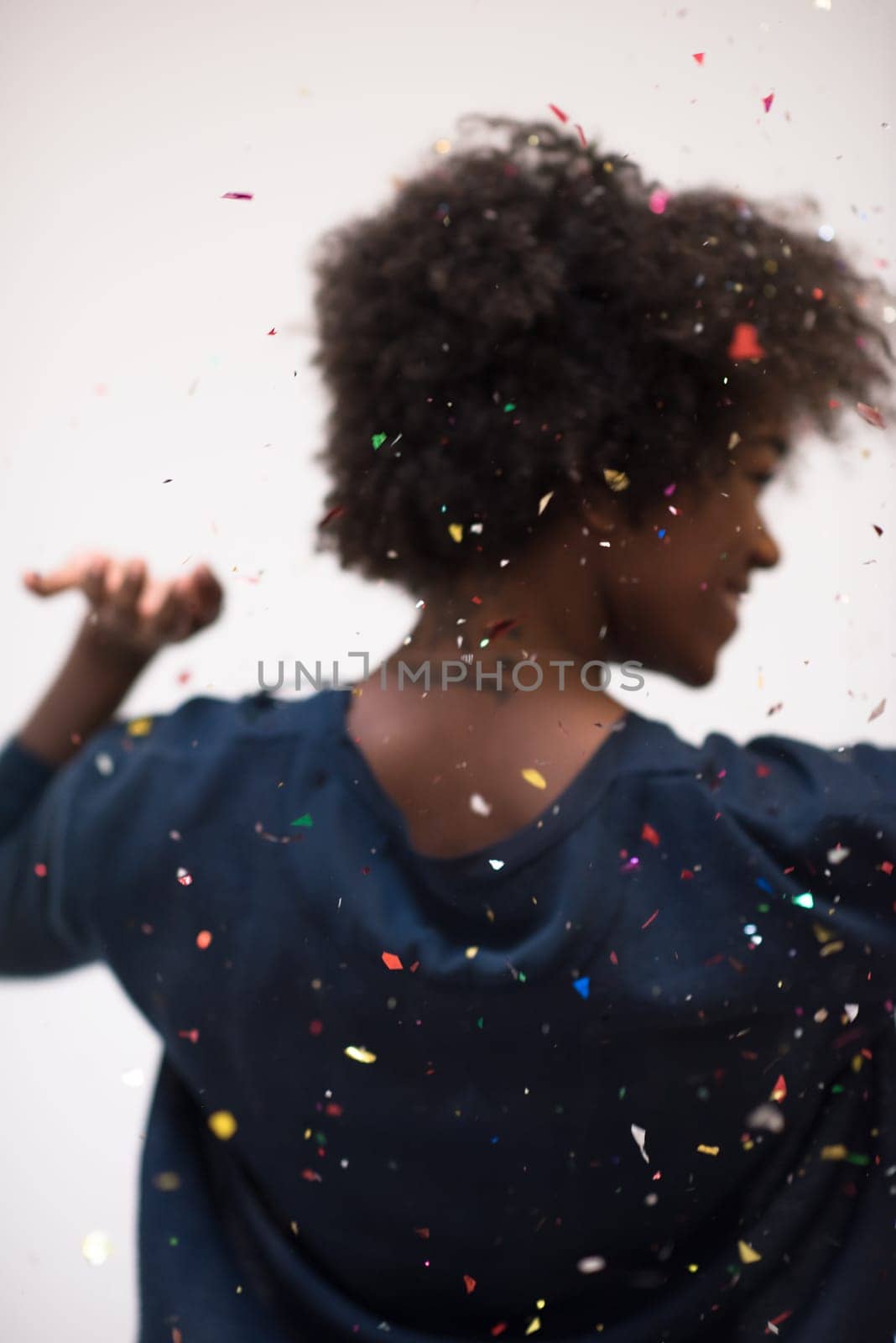 beautiful young black woman celebrating new year and chrismas party while blowing confetti decorations to camera