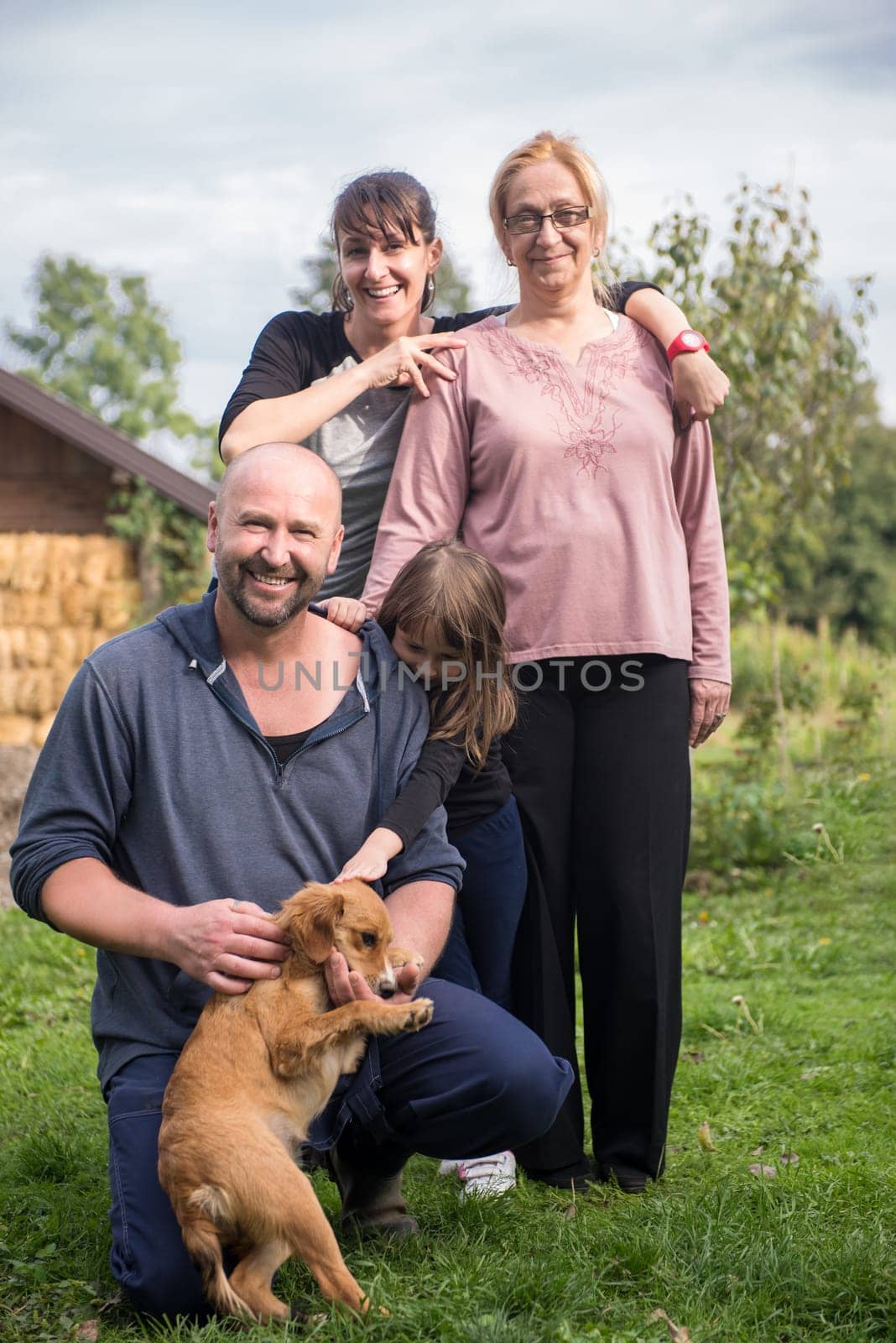 portrait of happy three generations family with dog at beautiful countryside farm