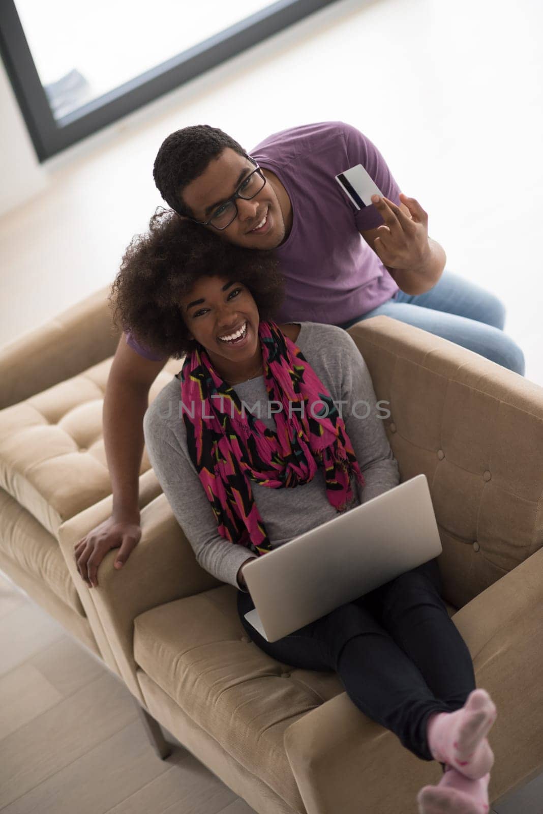 Happy young african american couple shopping online through laptop using credit card at home