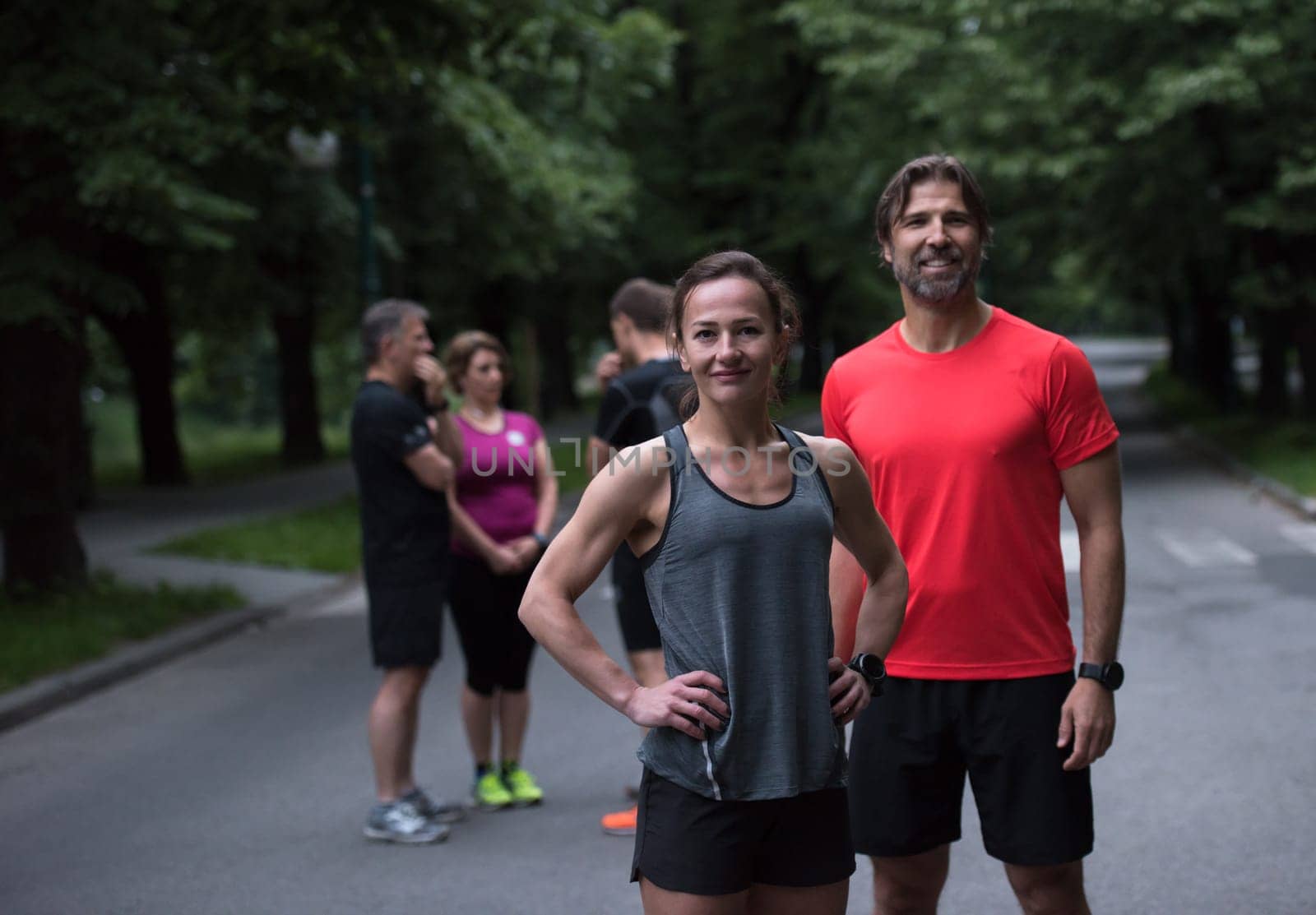 portrait of a healthy jogging couple with the rest of their running team in the background