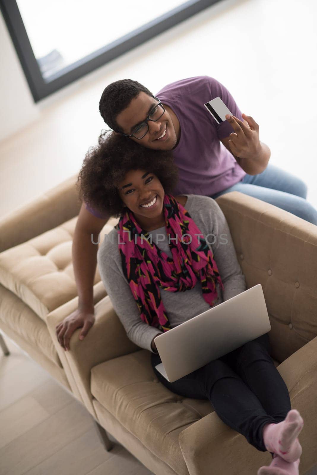 Happy young african american couple shopping online through laptop using credit card at home