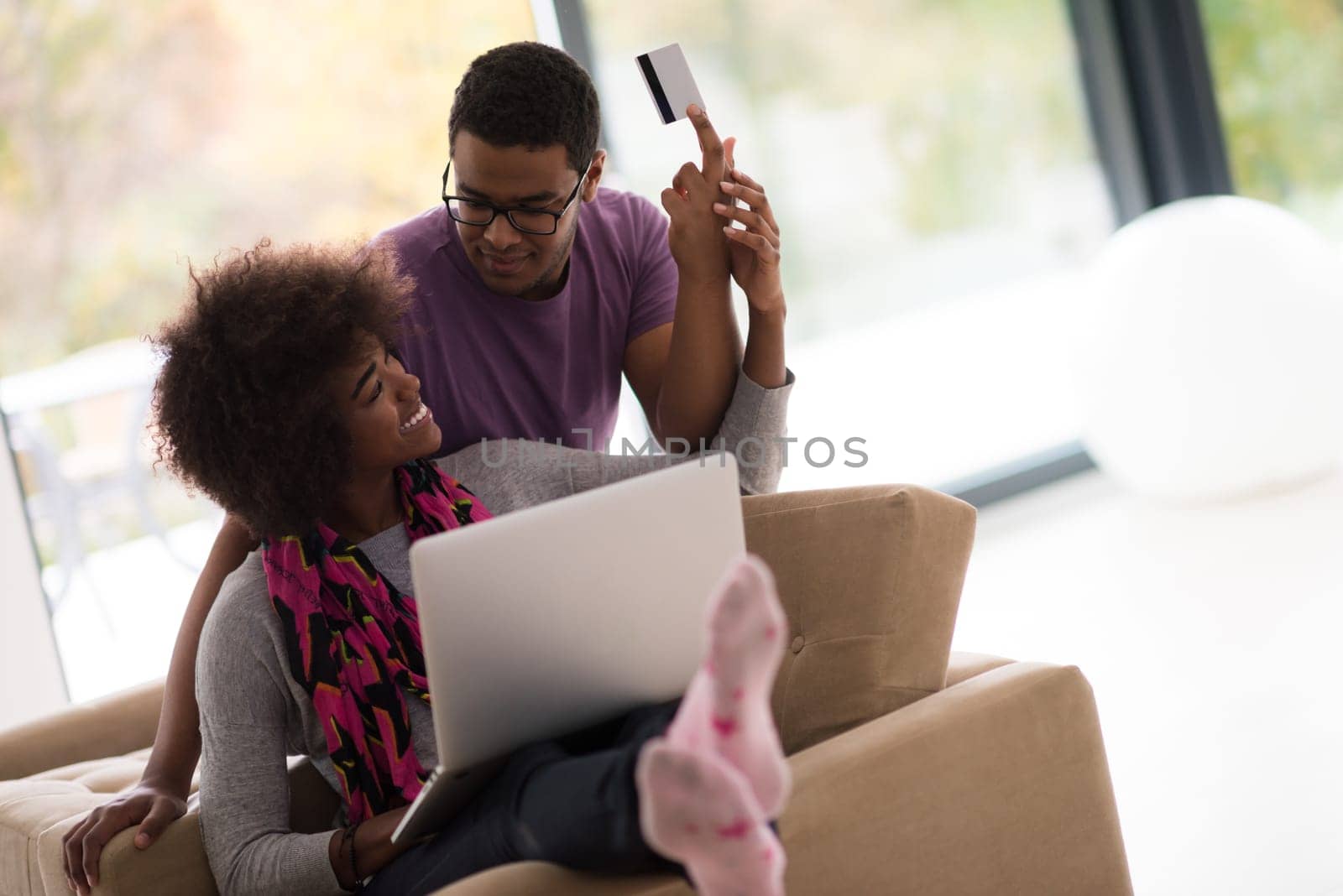 Happy young african american couple shopping online through laptop using credit card at home