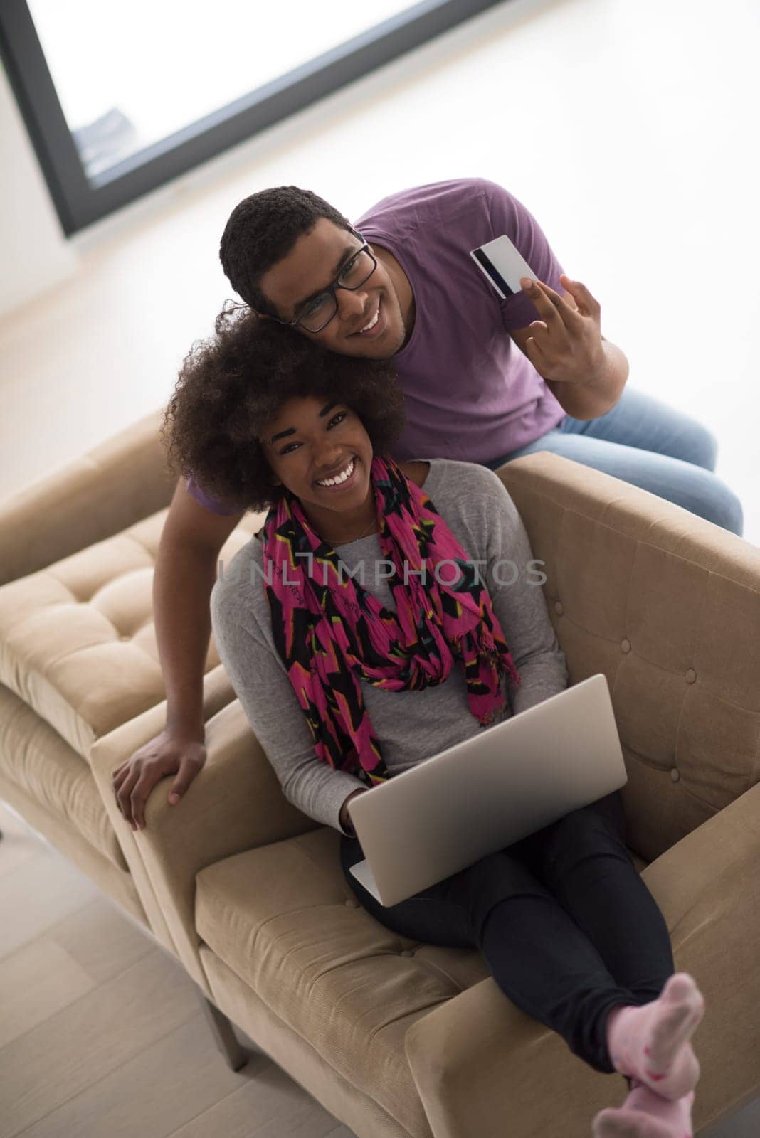 Happy young african american couple shopping online through laptop using credit card at home