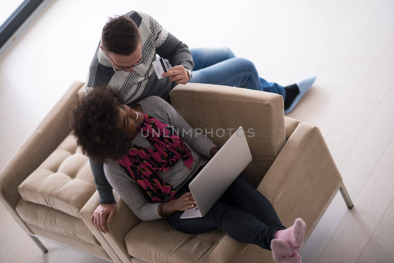 Happy young multiethnic couple shopping online through laptop using credit card at home