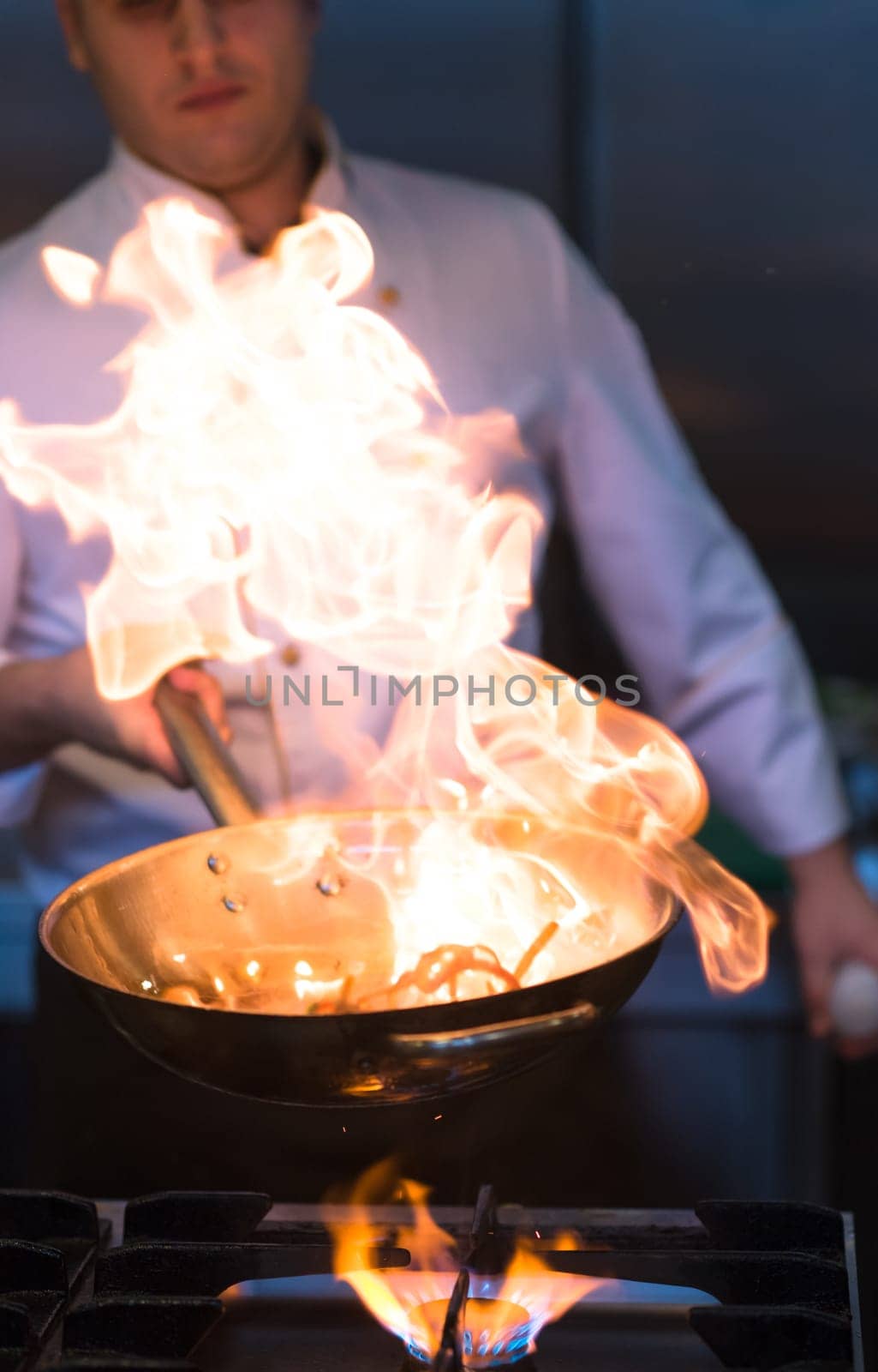 Chef cooking and doing flambe on food in restaurant kitchen