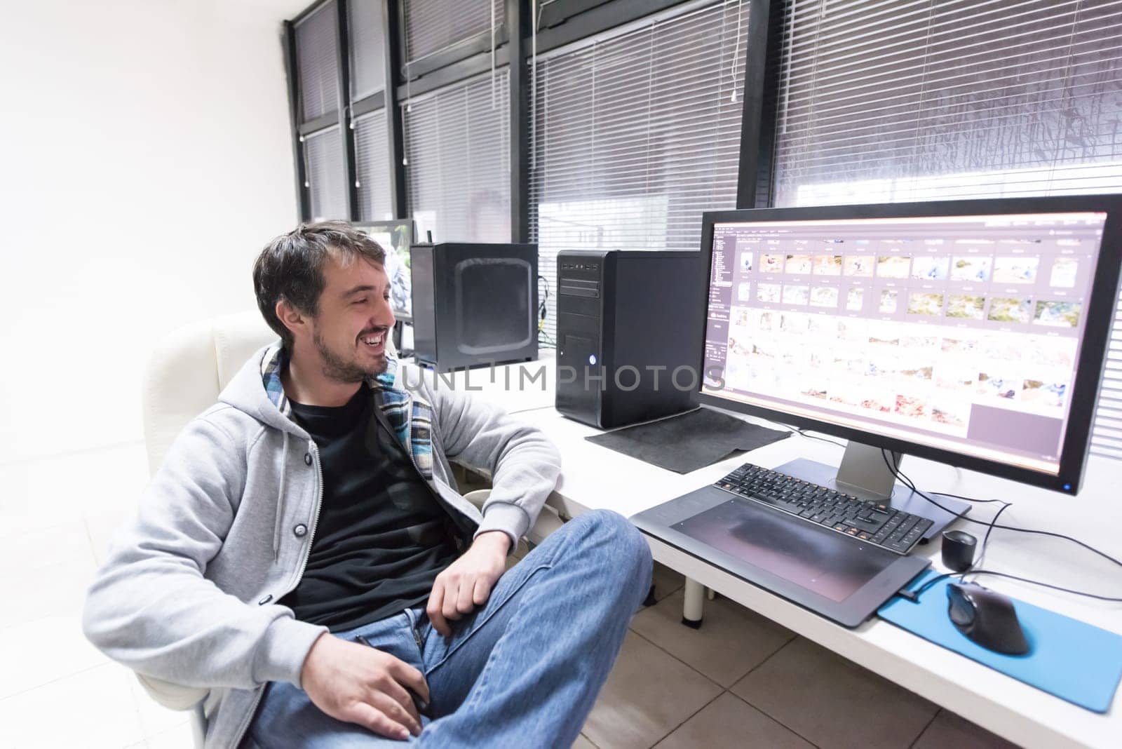 creative worker, photo editor working on graphic tablet at his desktop computer at small startup office