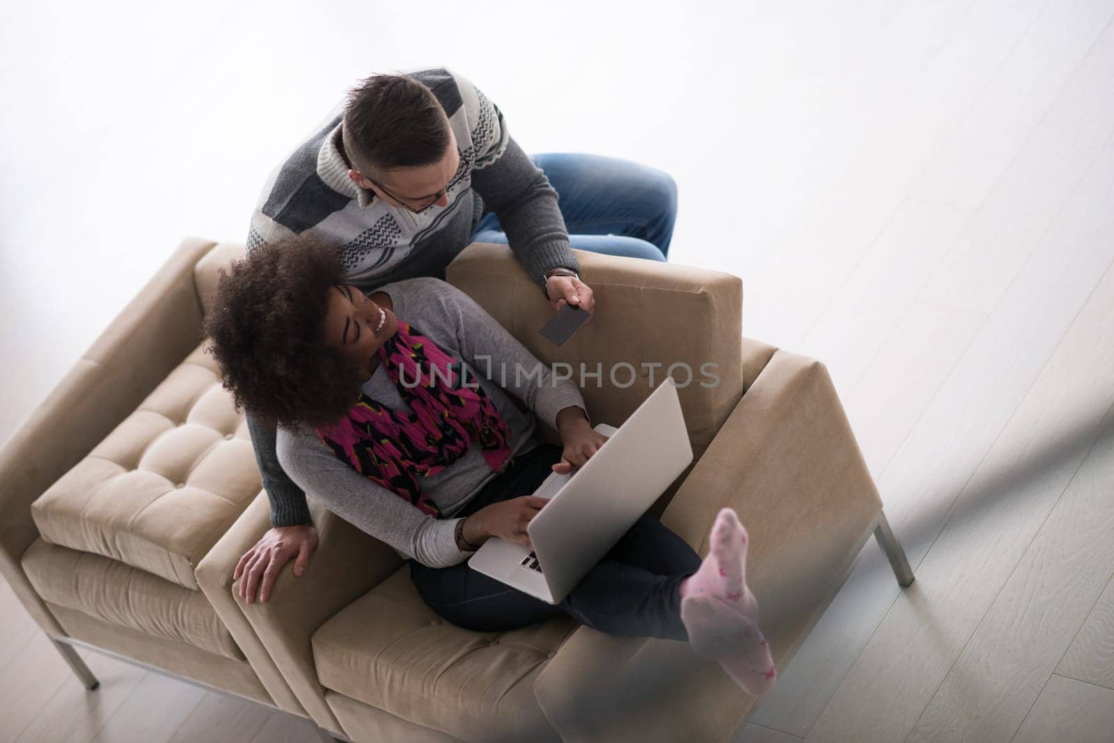 Happy young multiethnic couple shopping online through laptop using credit card at home