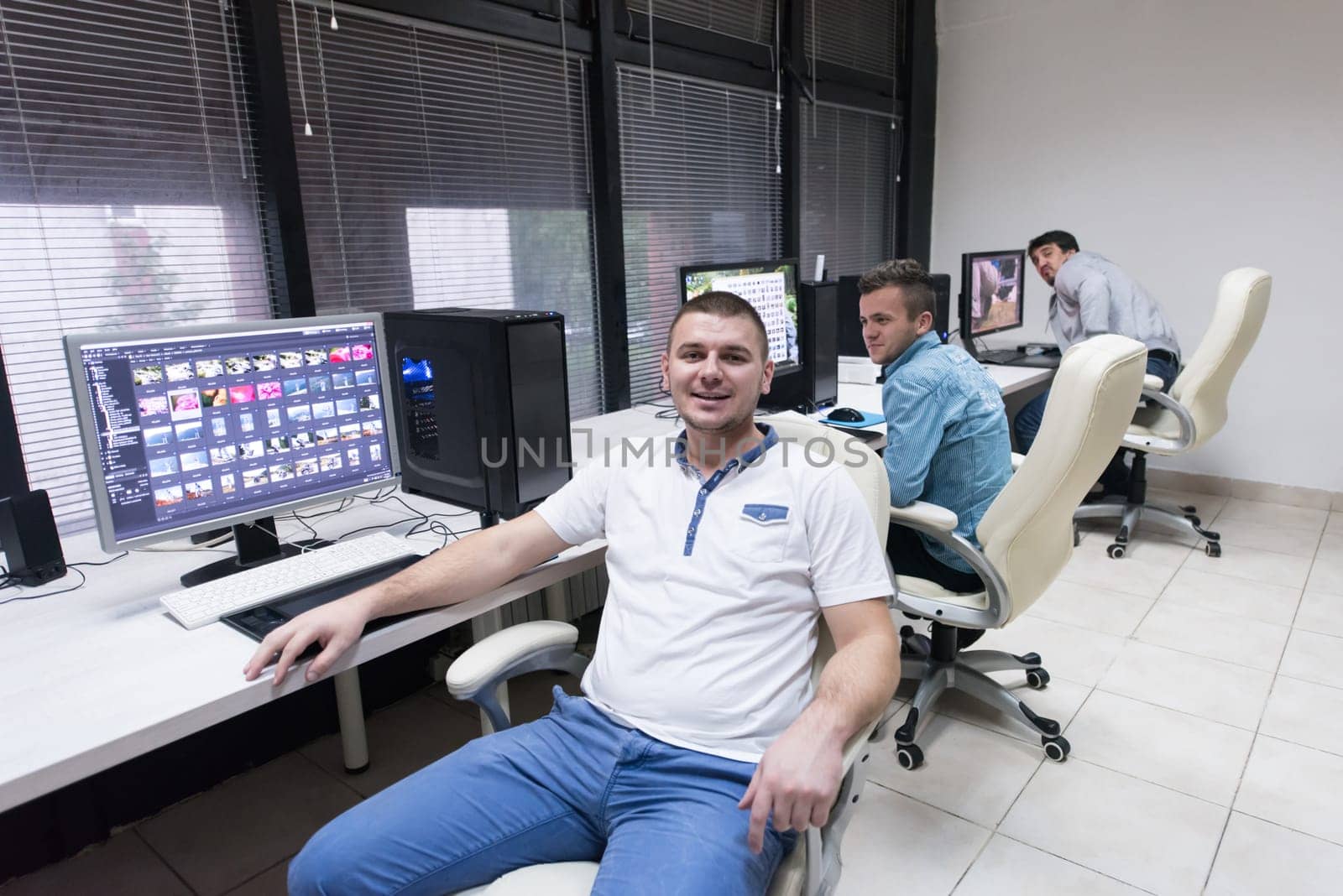 creative worker, photo editor working on graphic tablet at his desktop computer at small startup office