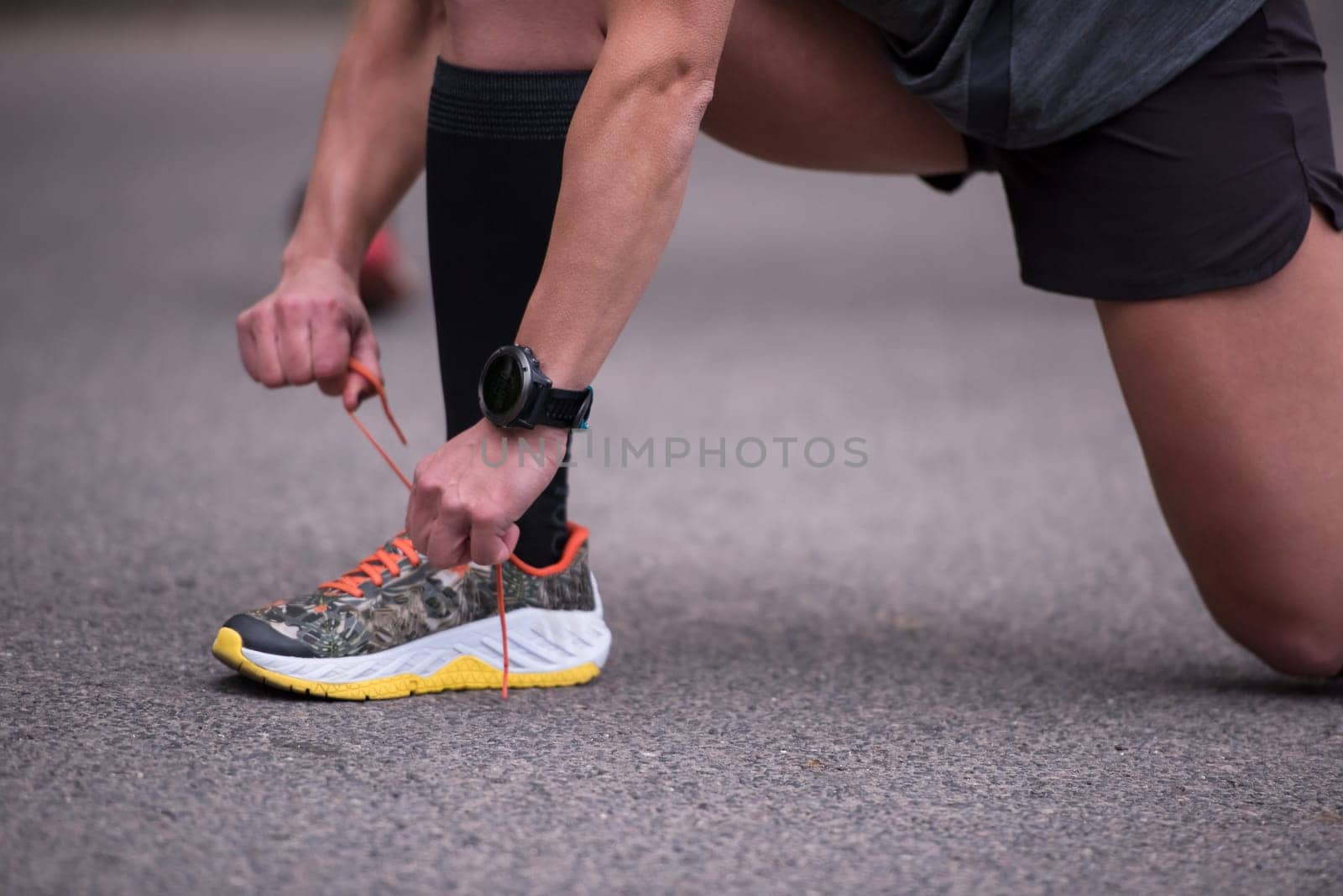 woman tying running shoes laces getting ready to run on city park at  morning