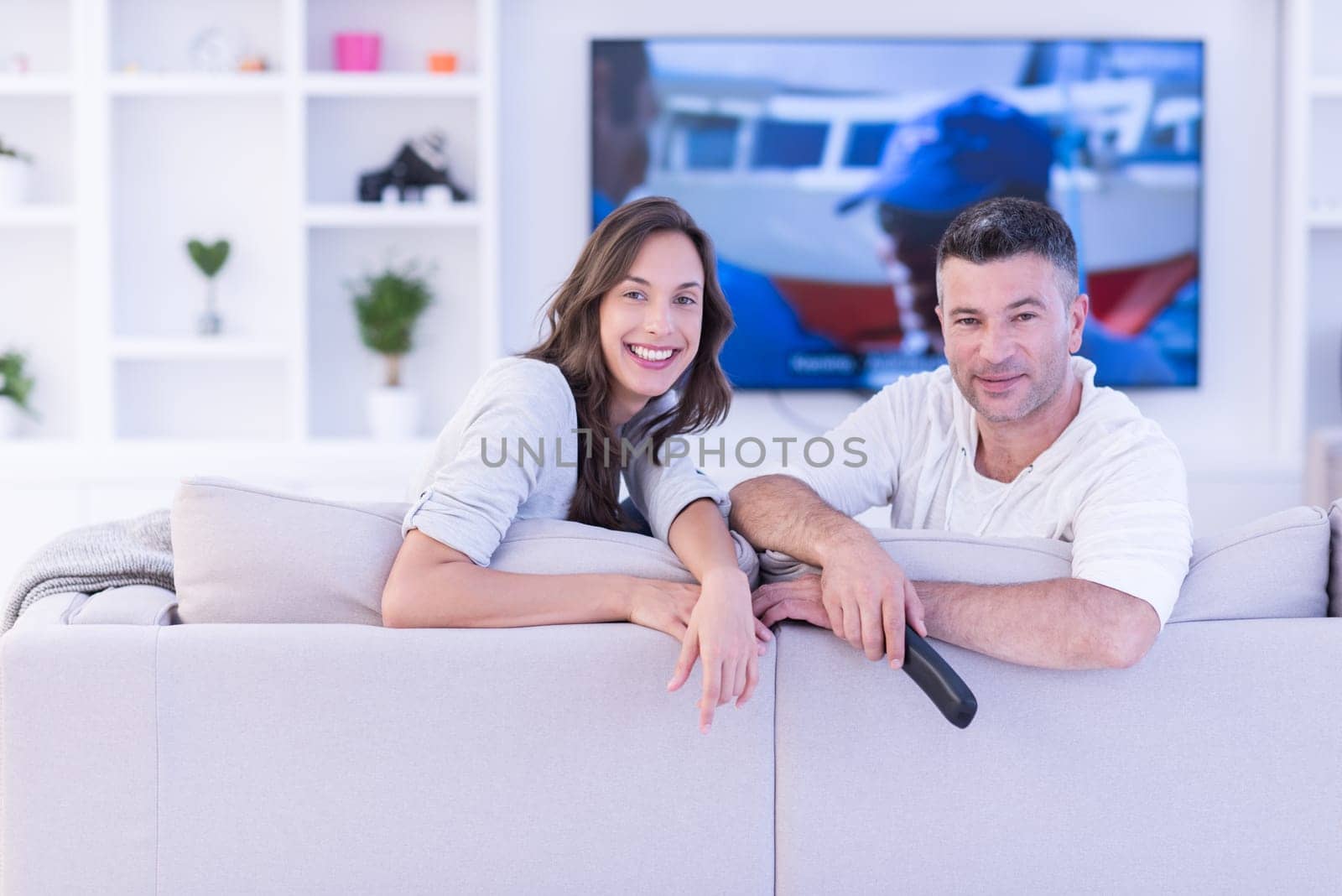Young couple on the sofa watching television together in their luxury home
