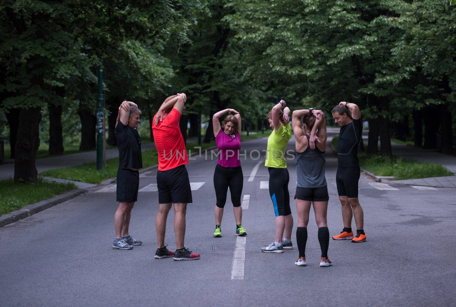 healthy runners team warming up and stretching in city park before morning training