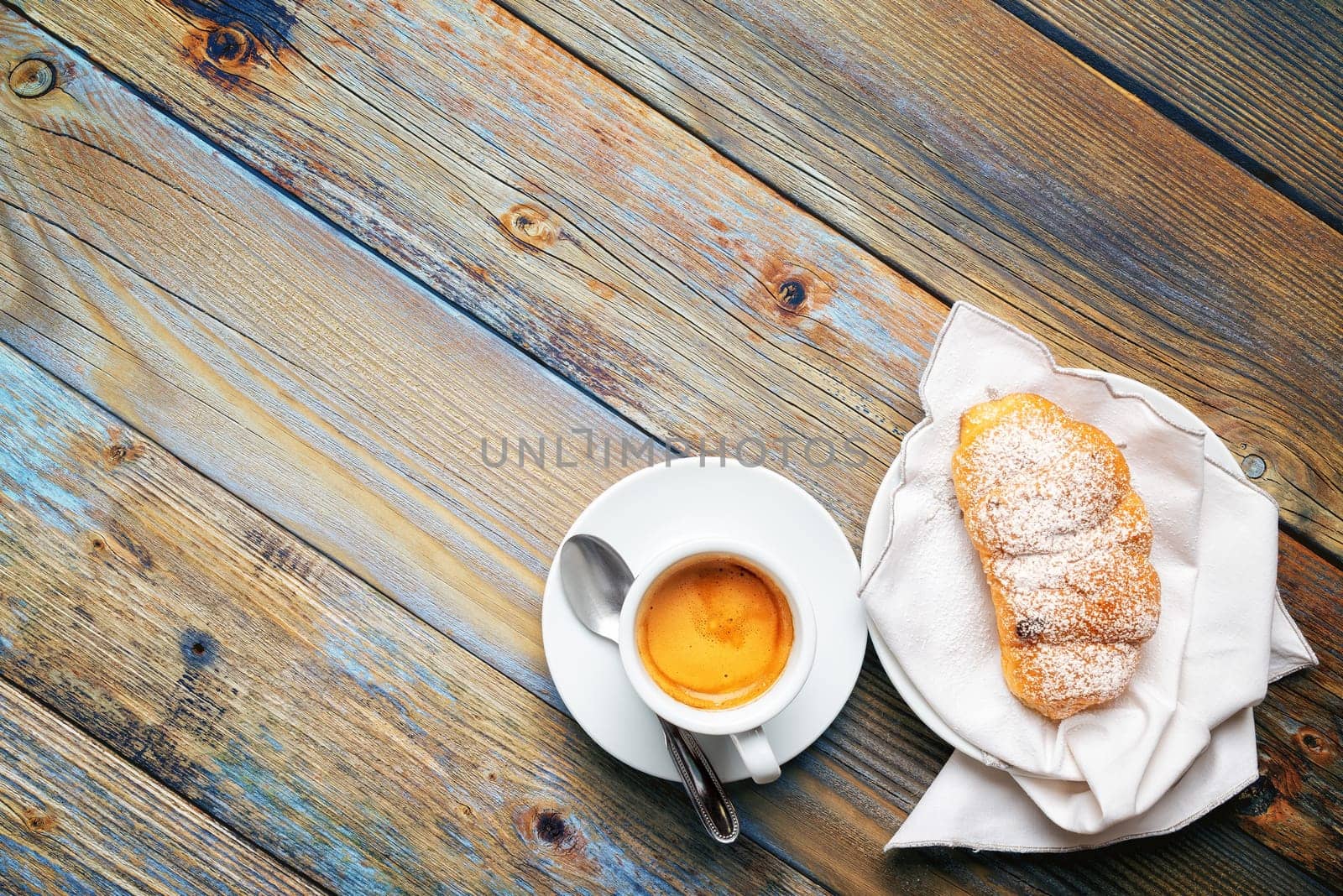 View from above. Cup of hot Italian espresso coffee and croissants on a light blue rustic wooden background. Food and drink. Lifestyle.