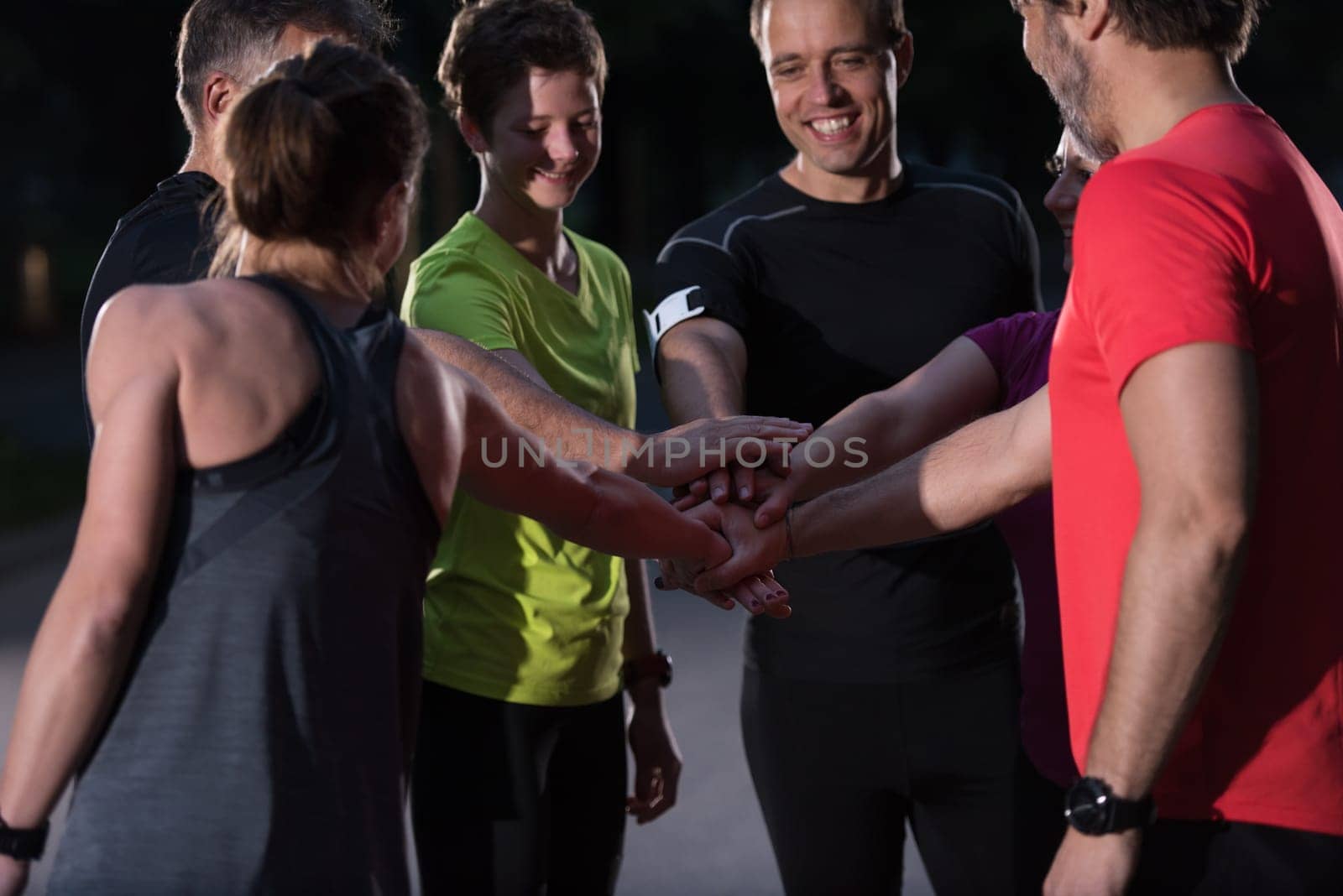 Group of healthy runners giving high five to each other while celebrating success after a training session.