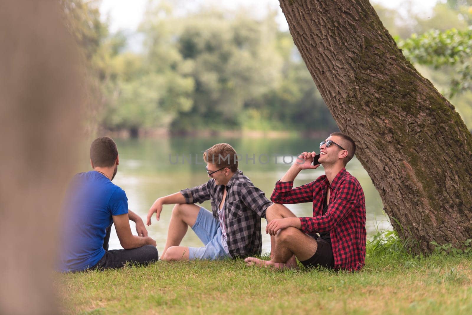 Group of young  men enjoying the nature sitting on the bank of the river