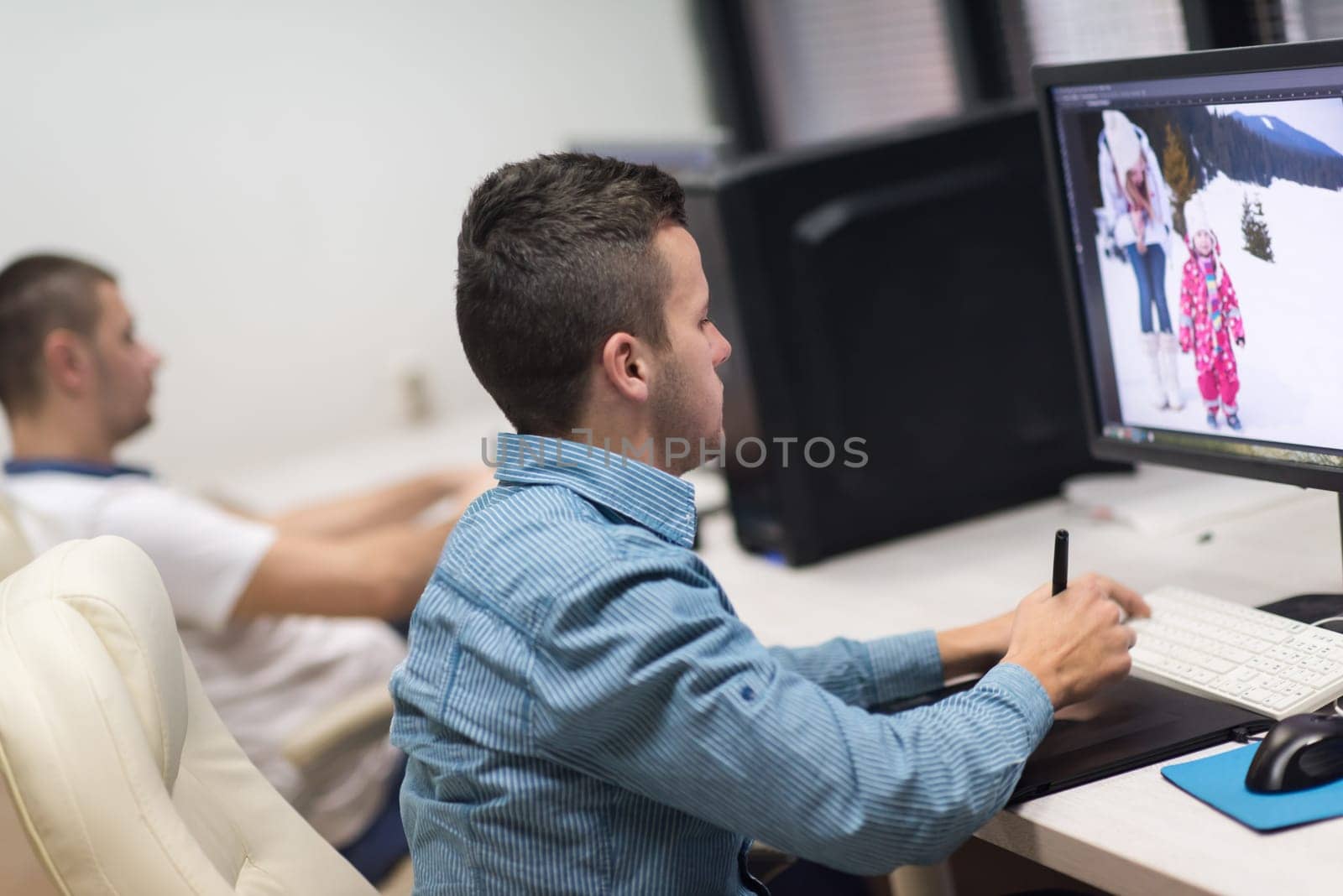 photo editors working with graphic tablet and pen on photographs in retouching studio