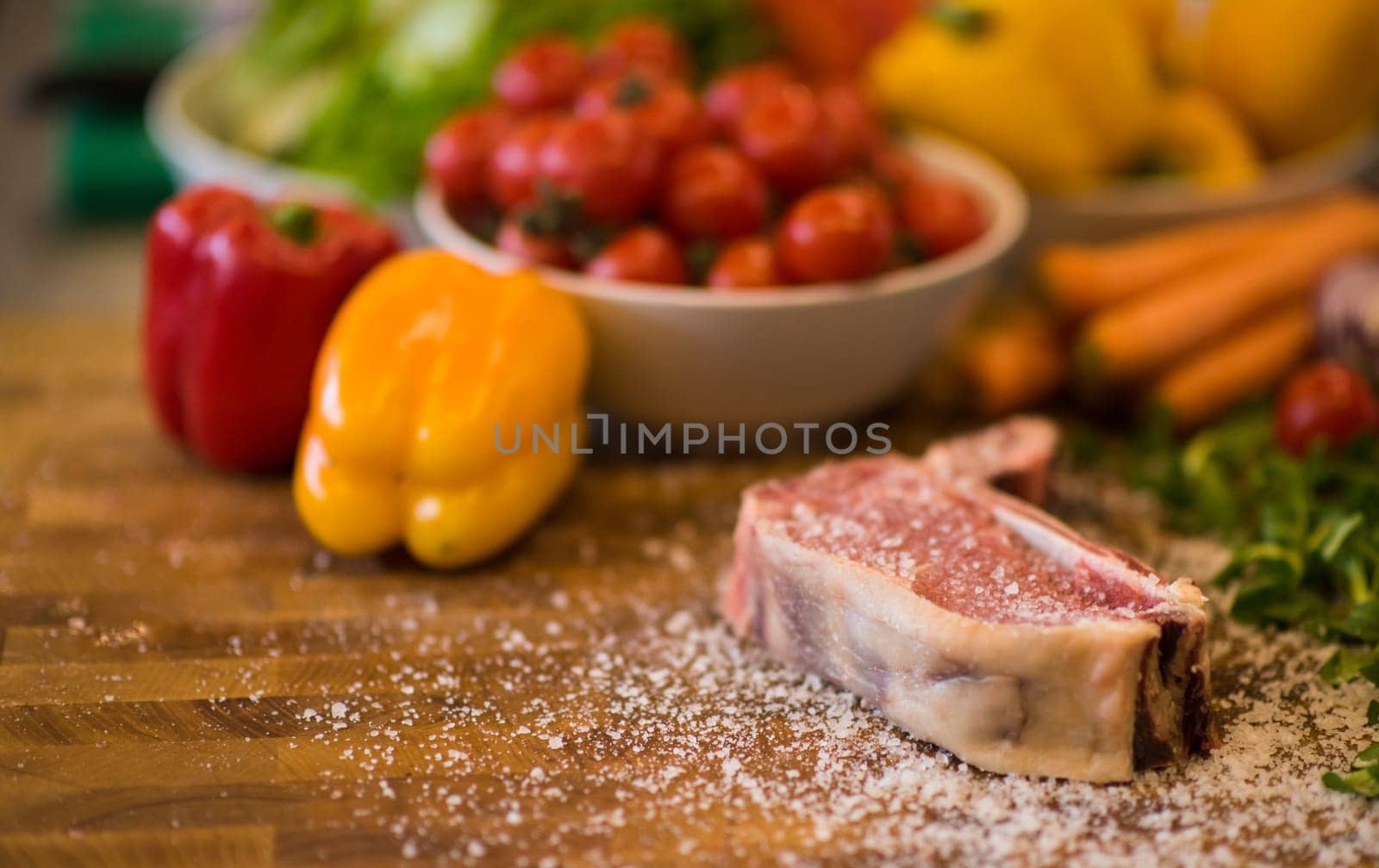 Juicy slice of raw steak  with vegetables around on a wooden table