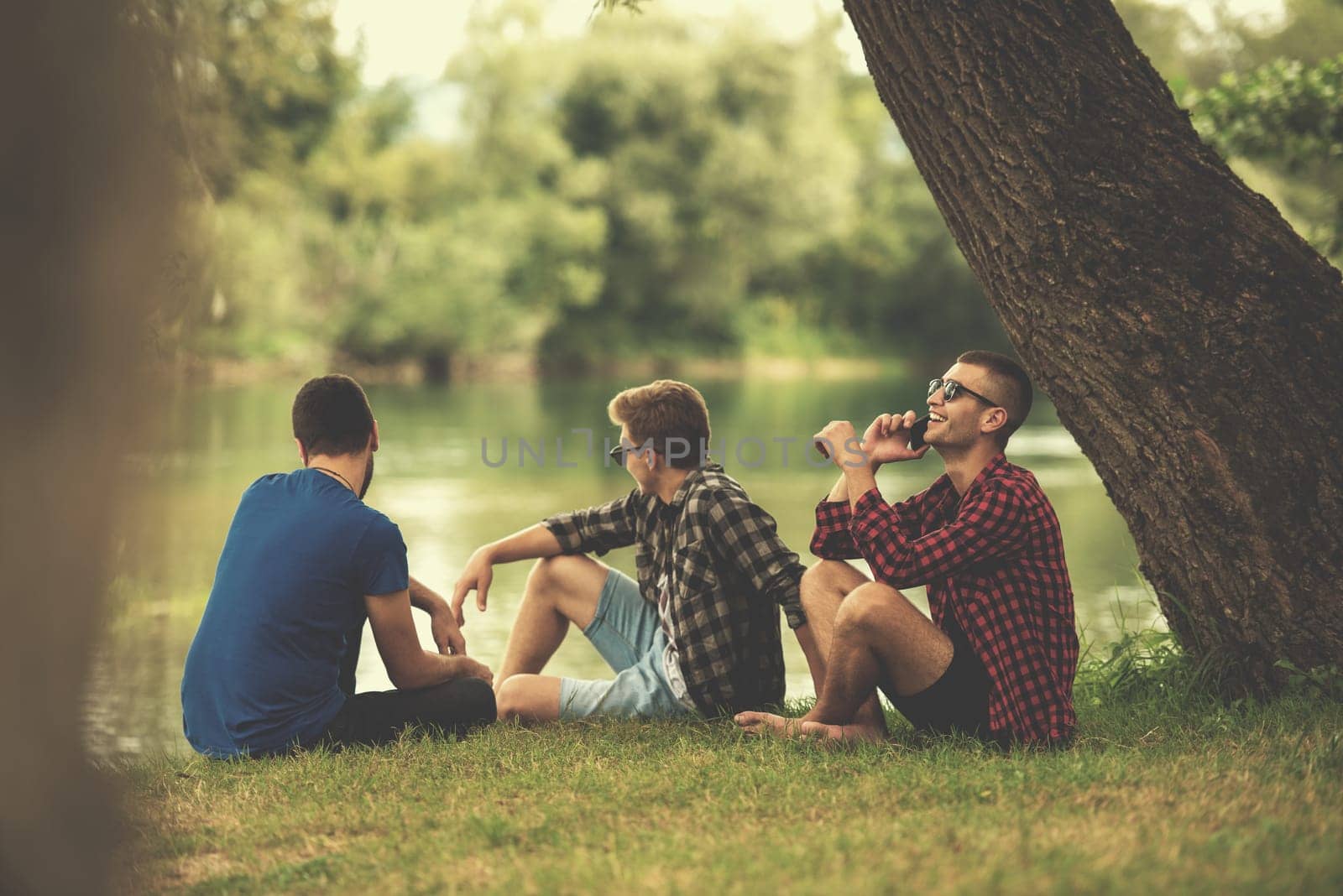 Group of young  men enjoying the nature sitting on the bank of the river