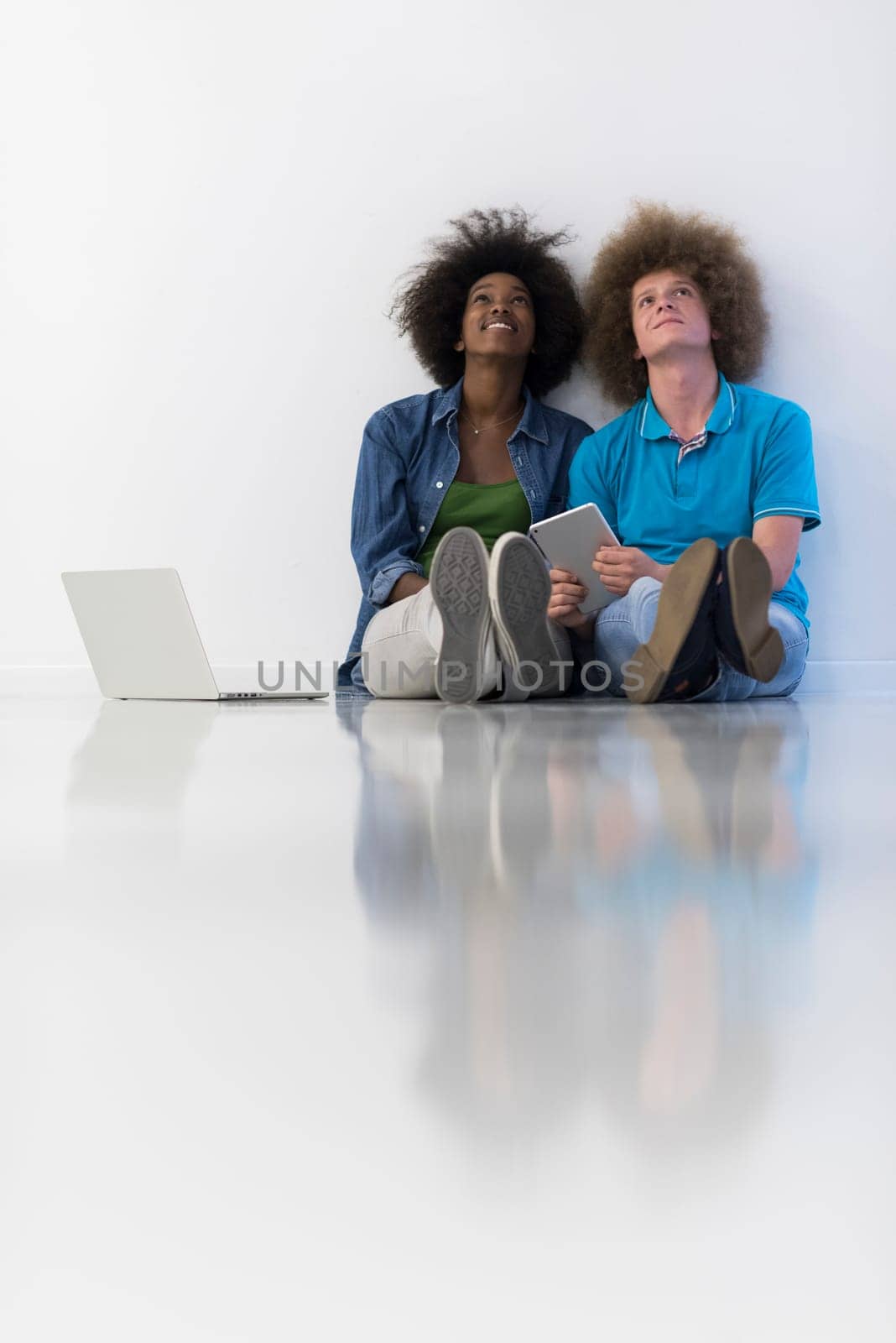startup business and new mobile technology concept with young multiethnic couple in modern bright office interior working on laptop and tablet computer on new creative project and brainstorming