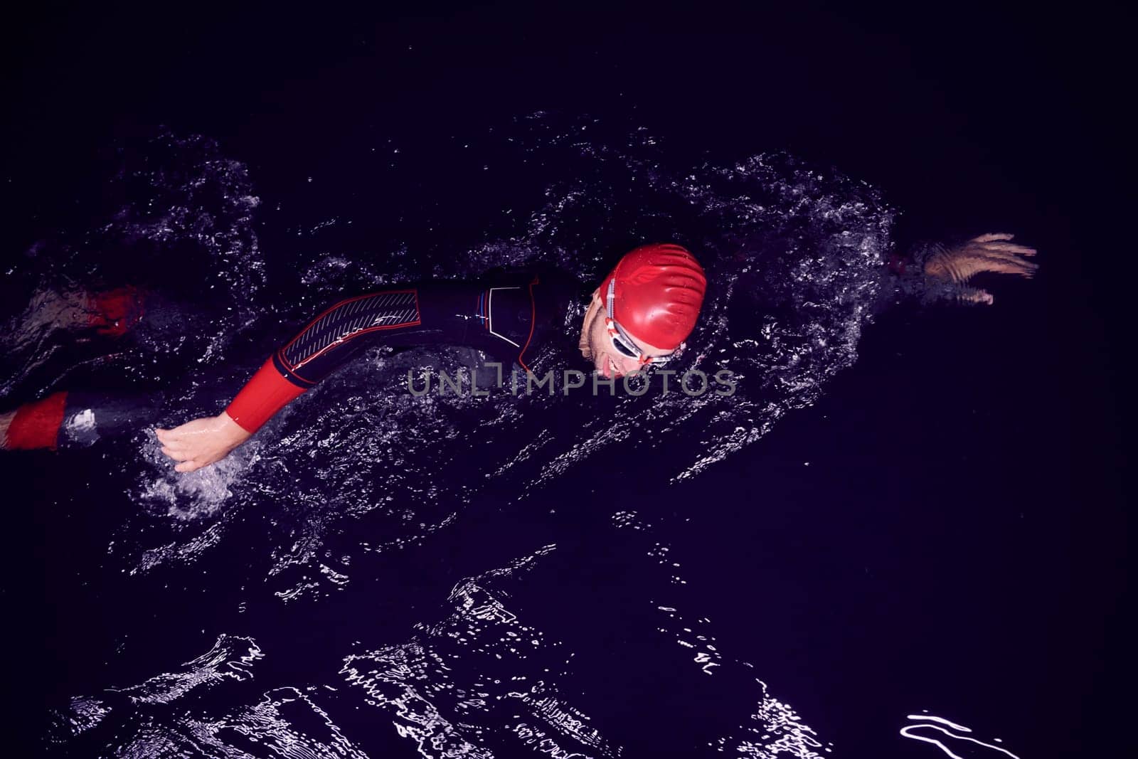 triathlon swimmer have extreme training  on dark night wearing wetsuit concept of strength and endurance