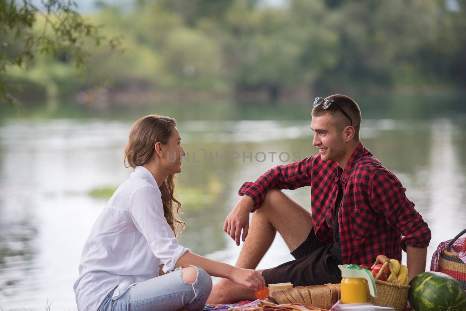 Couple in love enjoying picnic time drink and food in beautiful nature on the river bank