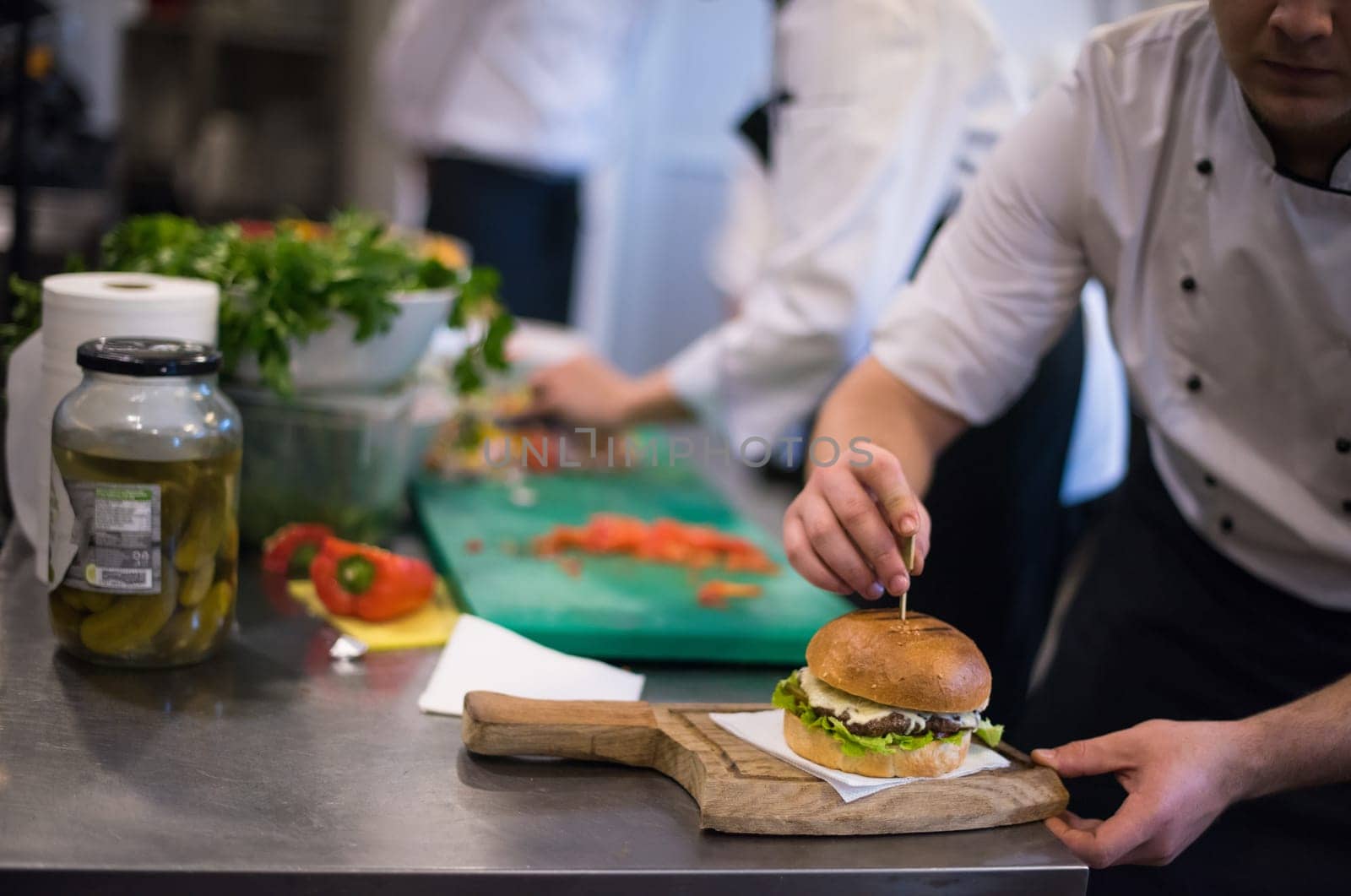 master chef putting toothpick on a burger in  restaurant kitchen
