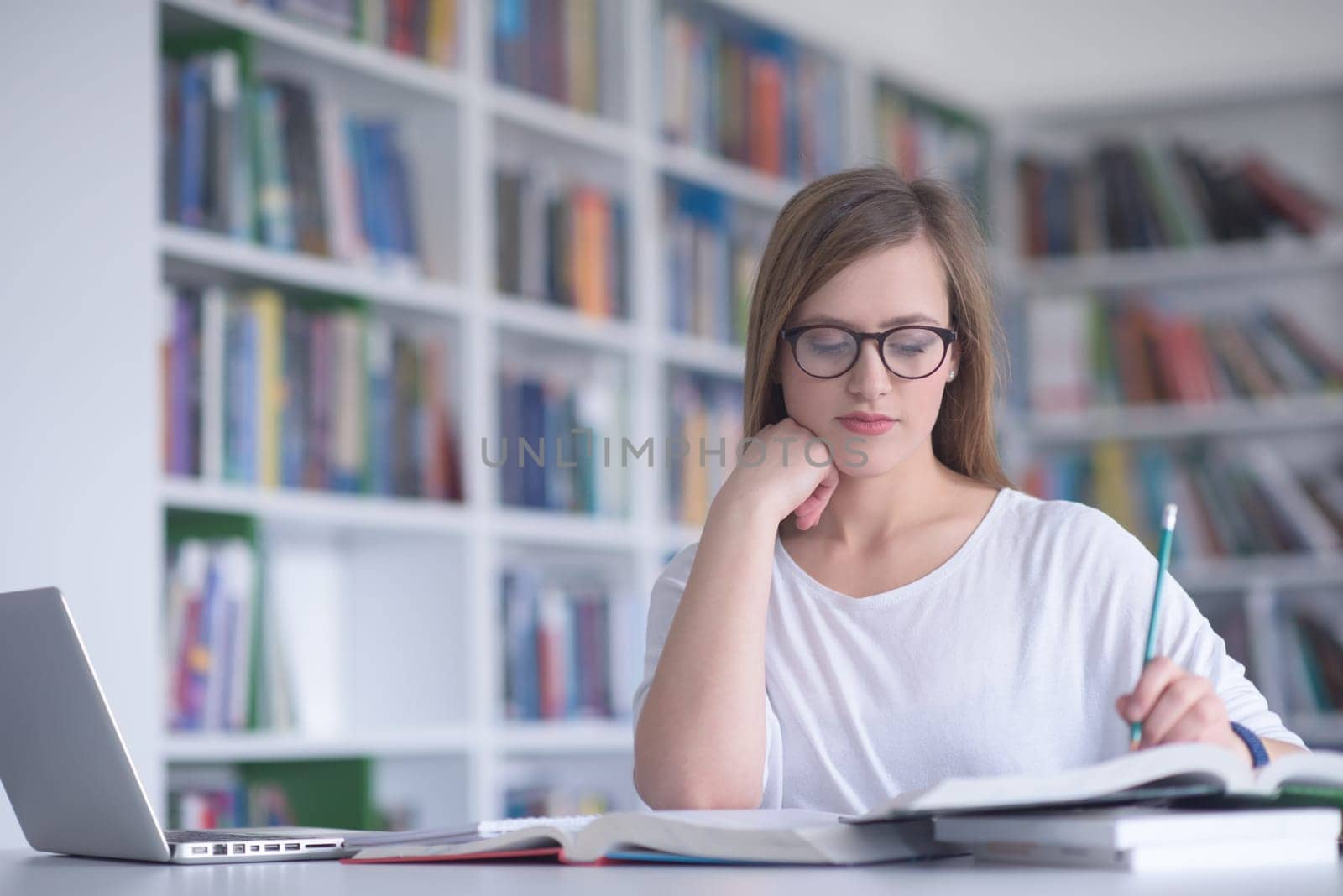 female student study in school library, using laptop and searching for informations on internet