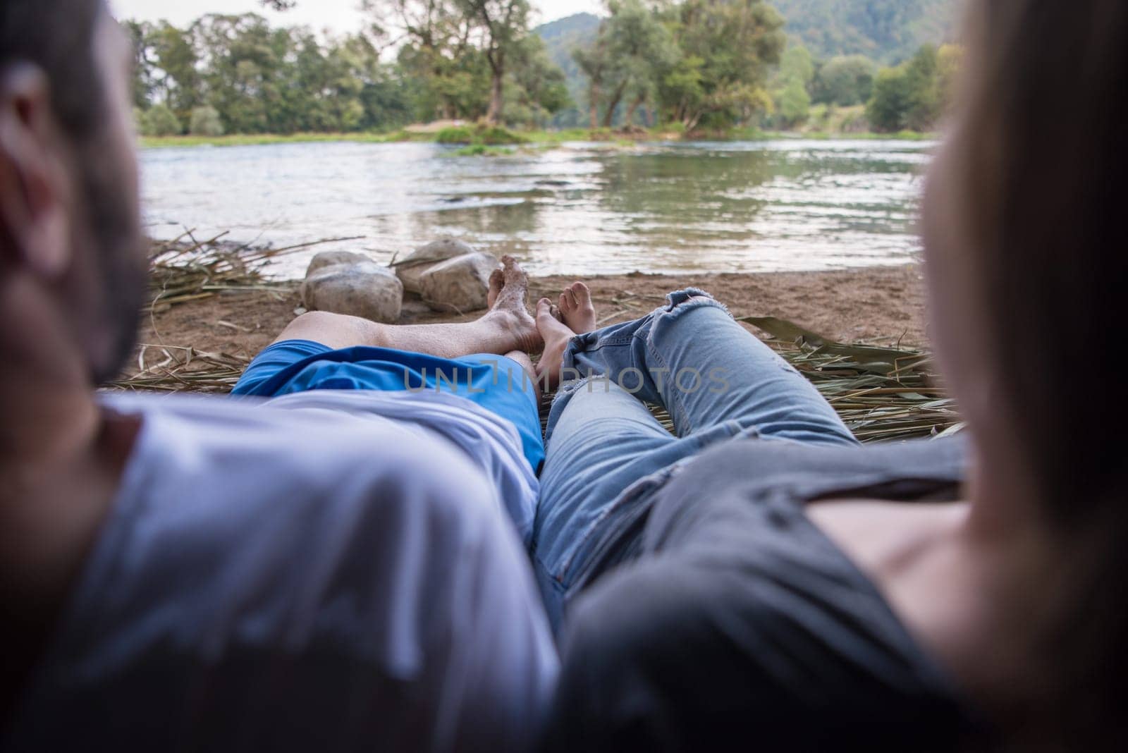 couple in love traveling and spending time together in straw tent while drinking hot tea by the river