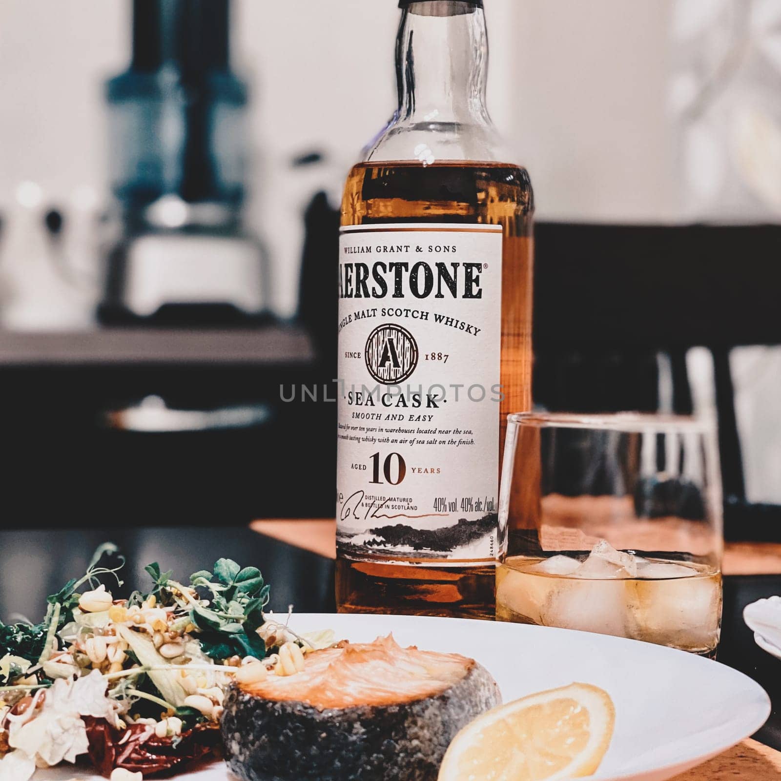 Salmon steak with a salad of herbs, spices and vegetables is served with whiskey. Supper. 07.02.2021. Samara, Russia.
