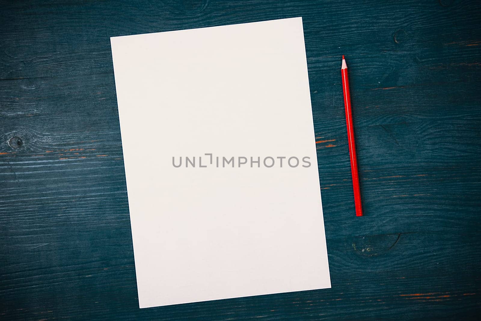 A blank white sheet and pencil for drawing on a wooden background with space for copying and lettering. Layout, mockup free space.