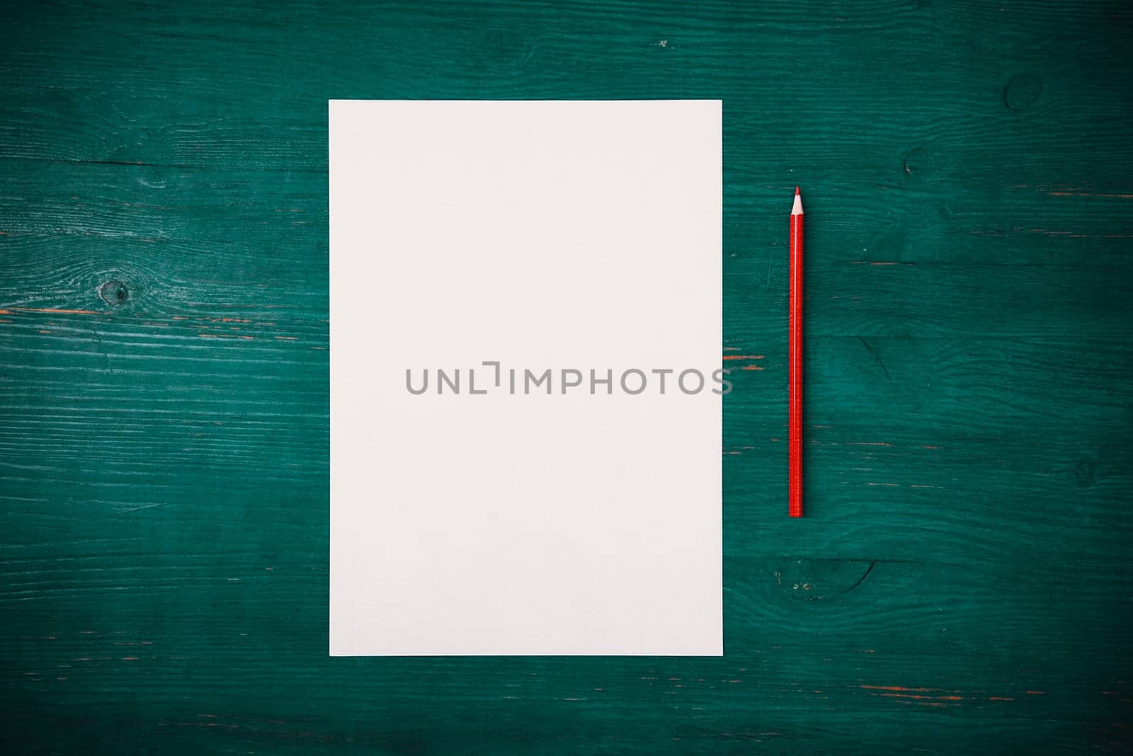 A blank white sheet and pencil for drawing on a wooden background with space for copying and lettering. Layout, mockup free space.