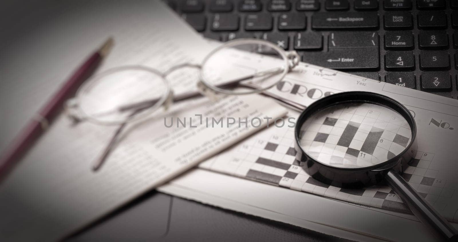 The glasses and old newspaper lying on the black open laptop. Selective focus