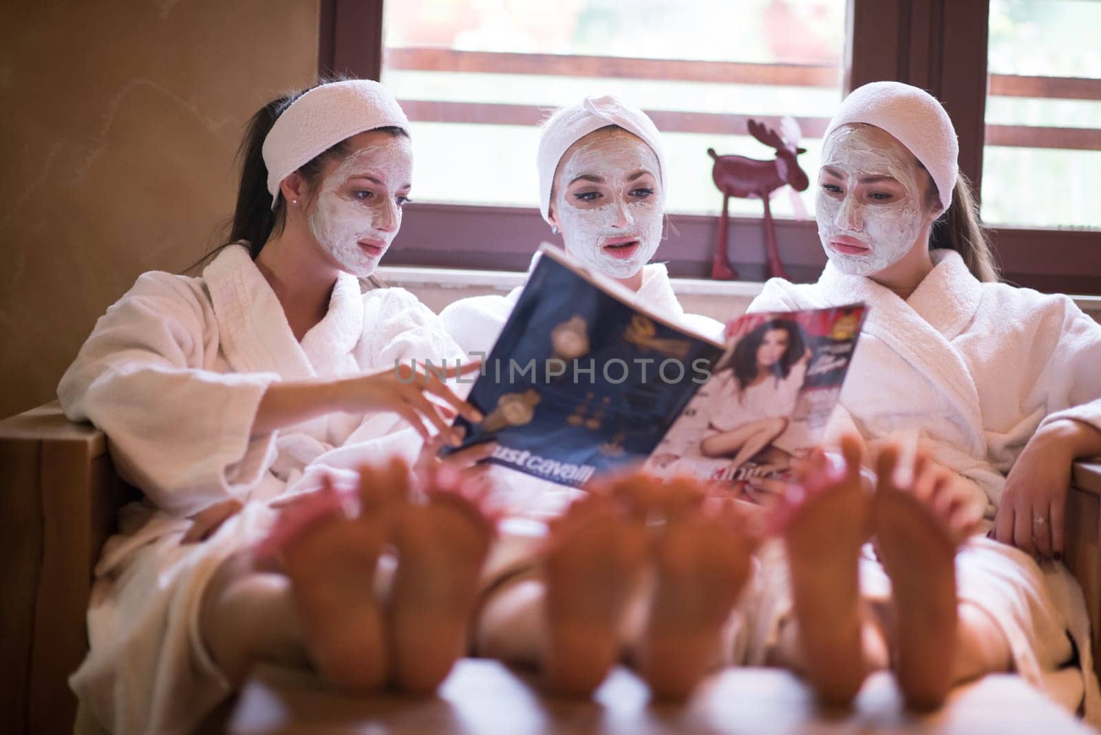 group of famale friends in spa have fun, celebrate bachelorette party with face mask